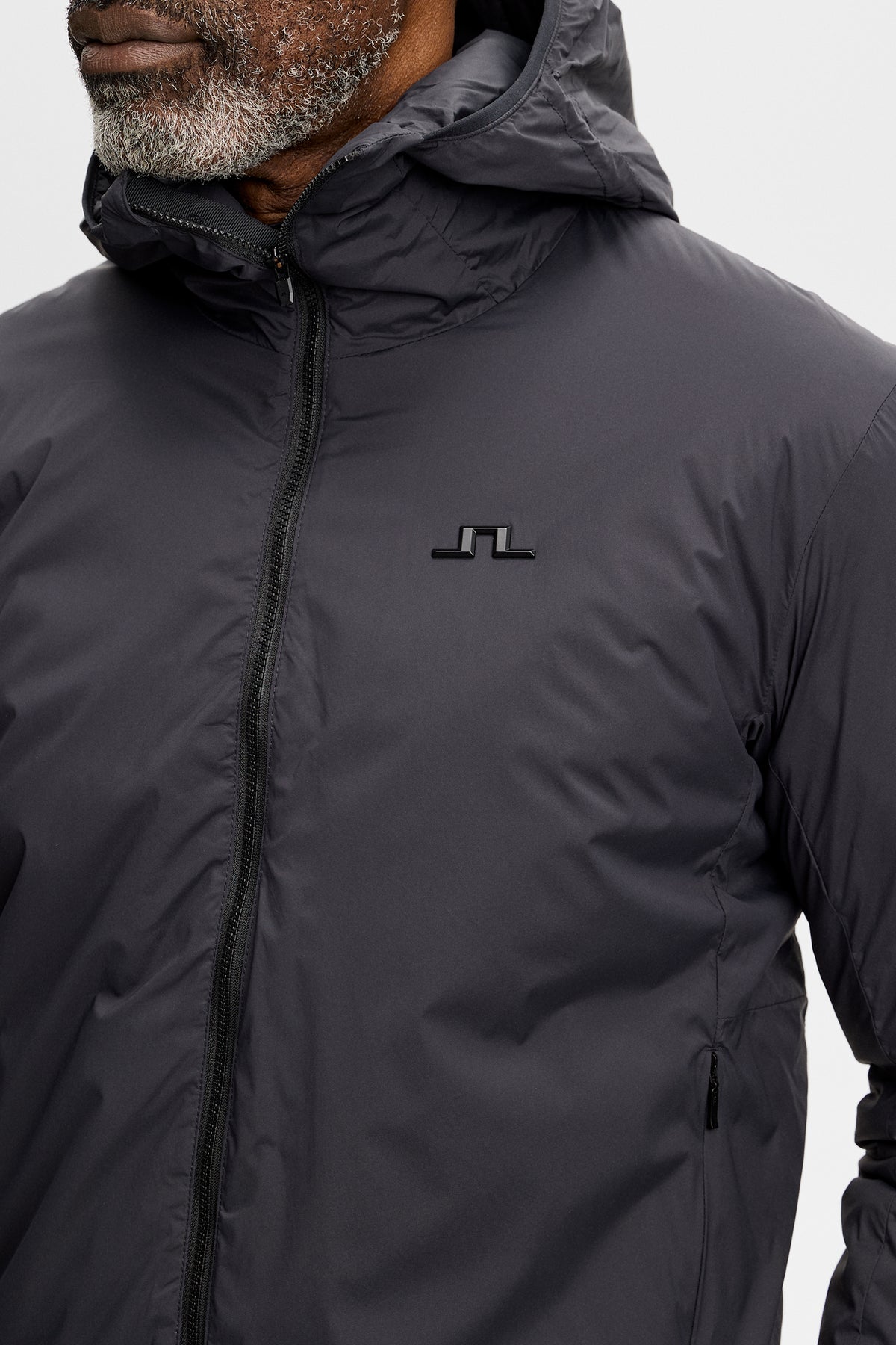 Close-up of the Clinton Hood jacket in black, showing the chest Bridge logo and front zipper.
