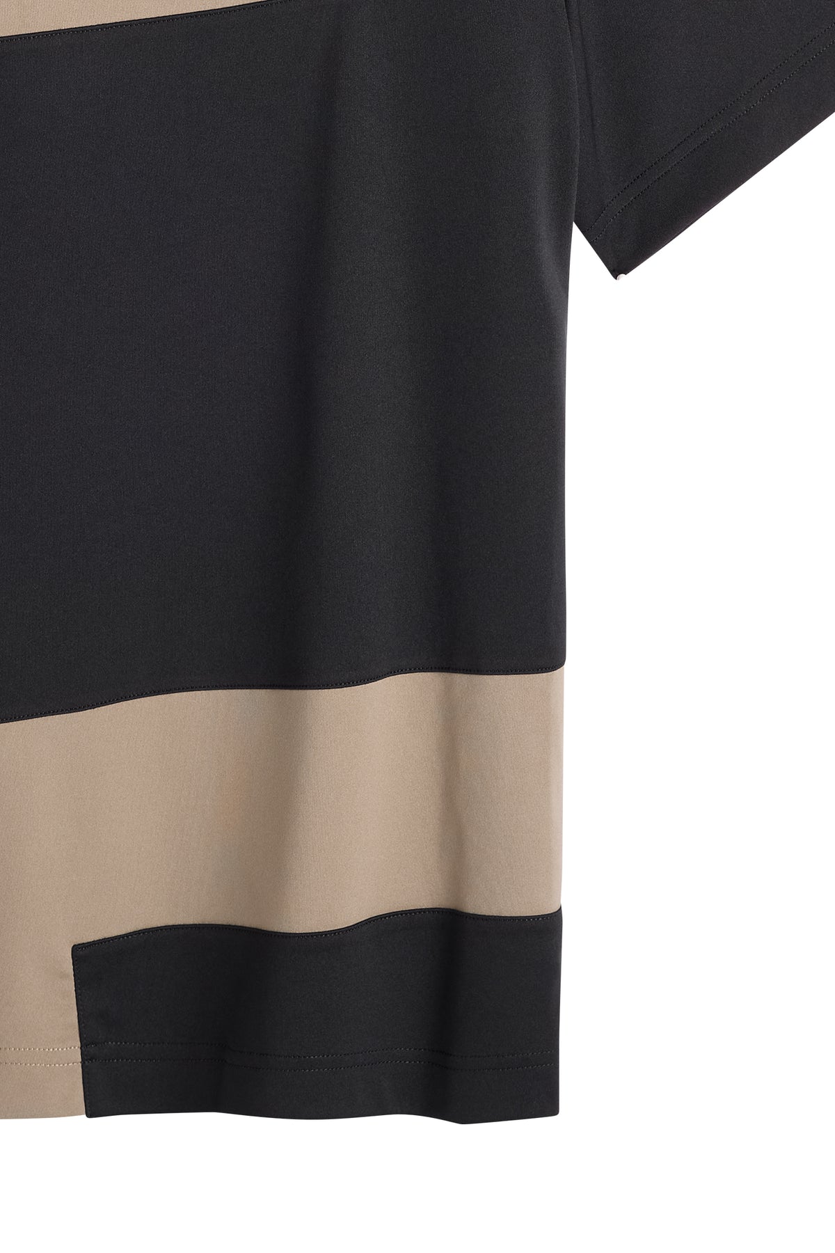 Detail shot of the black and beige Sidd Polo, highlighting the geometric contrast panels and hem.
