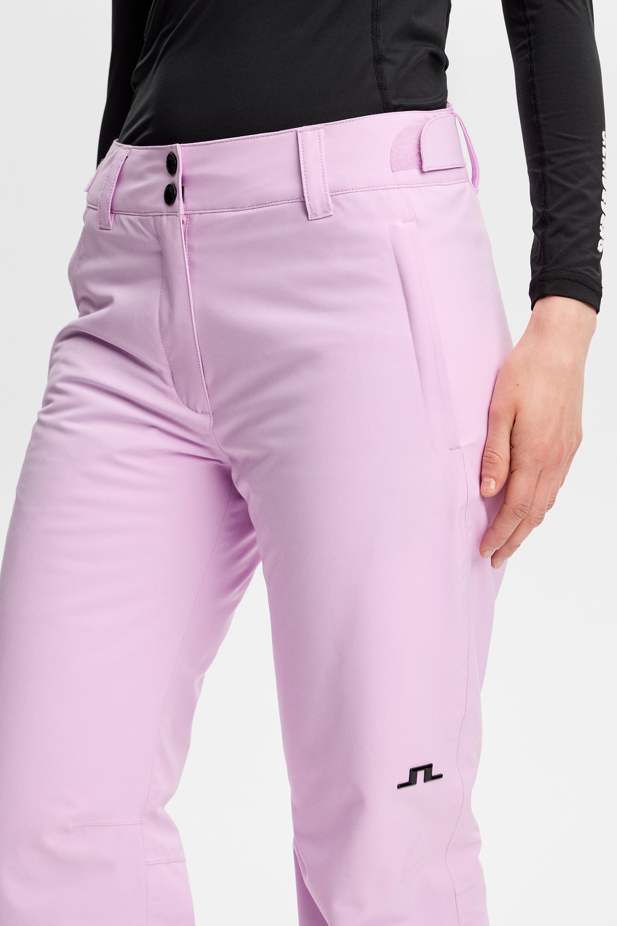 Detailansicht: Moeva Pant in Orchid Bouquet mit Gürtelschlaufen, Eingrifftasche und schwarzem Bridge-Logo auf dem Bein.