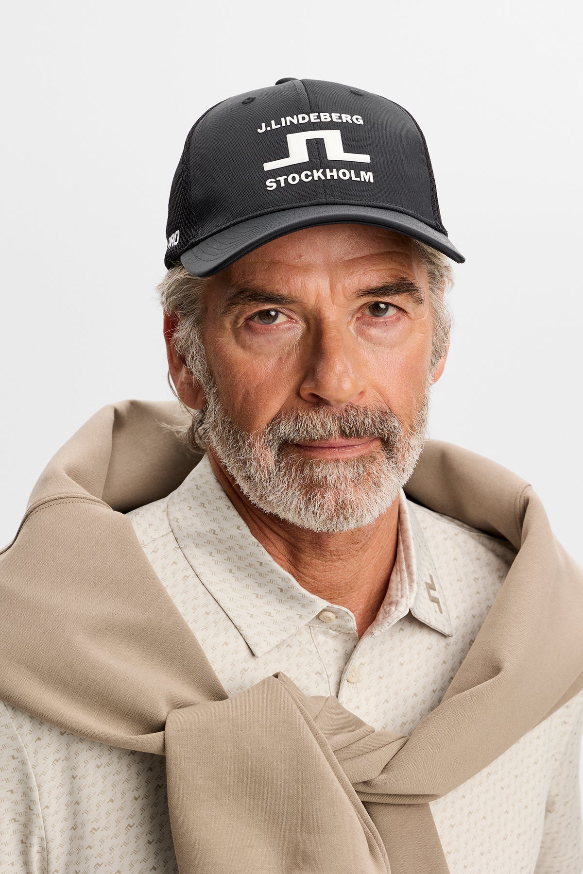 Sett forfra: Svart JL Pro Cap med hvit J.Lindeberg Stockholm-grafikk foran, på modell i studio.