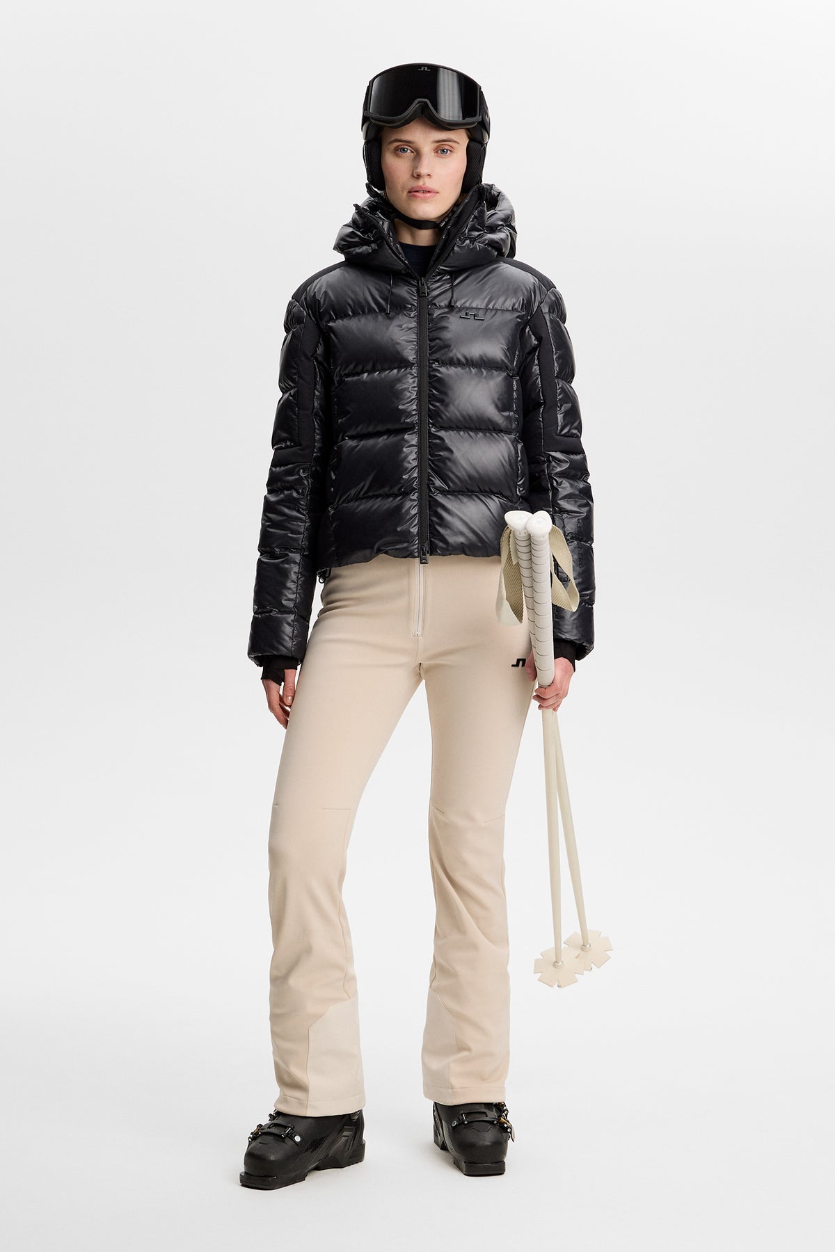 Vooraanzicht: Model draagt de Aviana Softshell Bib Pant in Moonbeam met een zwarte ski-jas en skistokken.