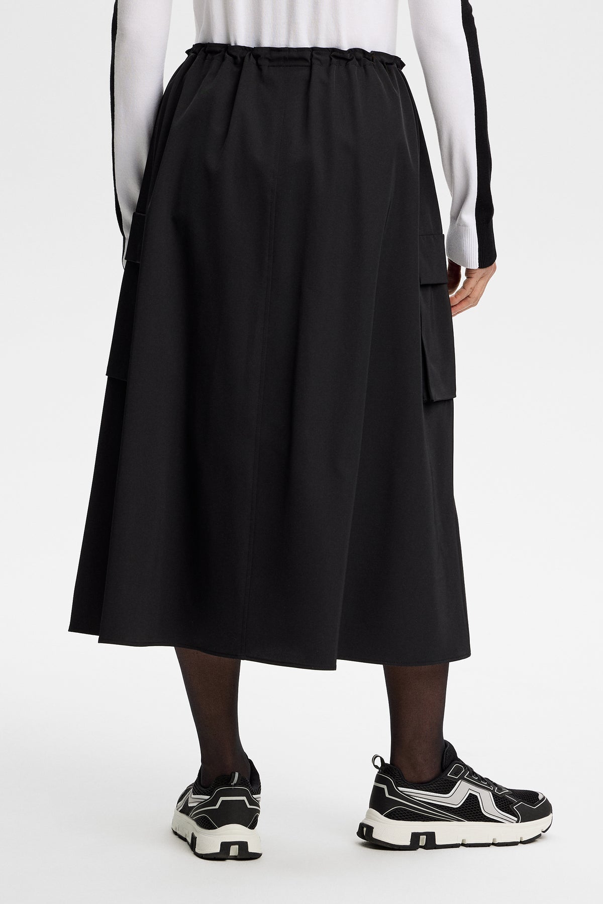 Vue de dos : Essa Tech Drape Skirt noire mi-longue à taille élastique et poches latérales à rabat.