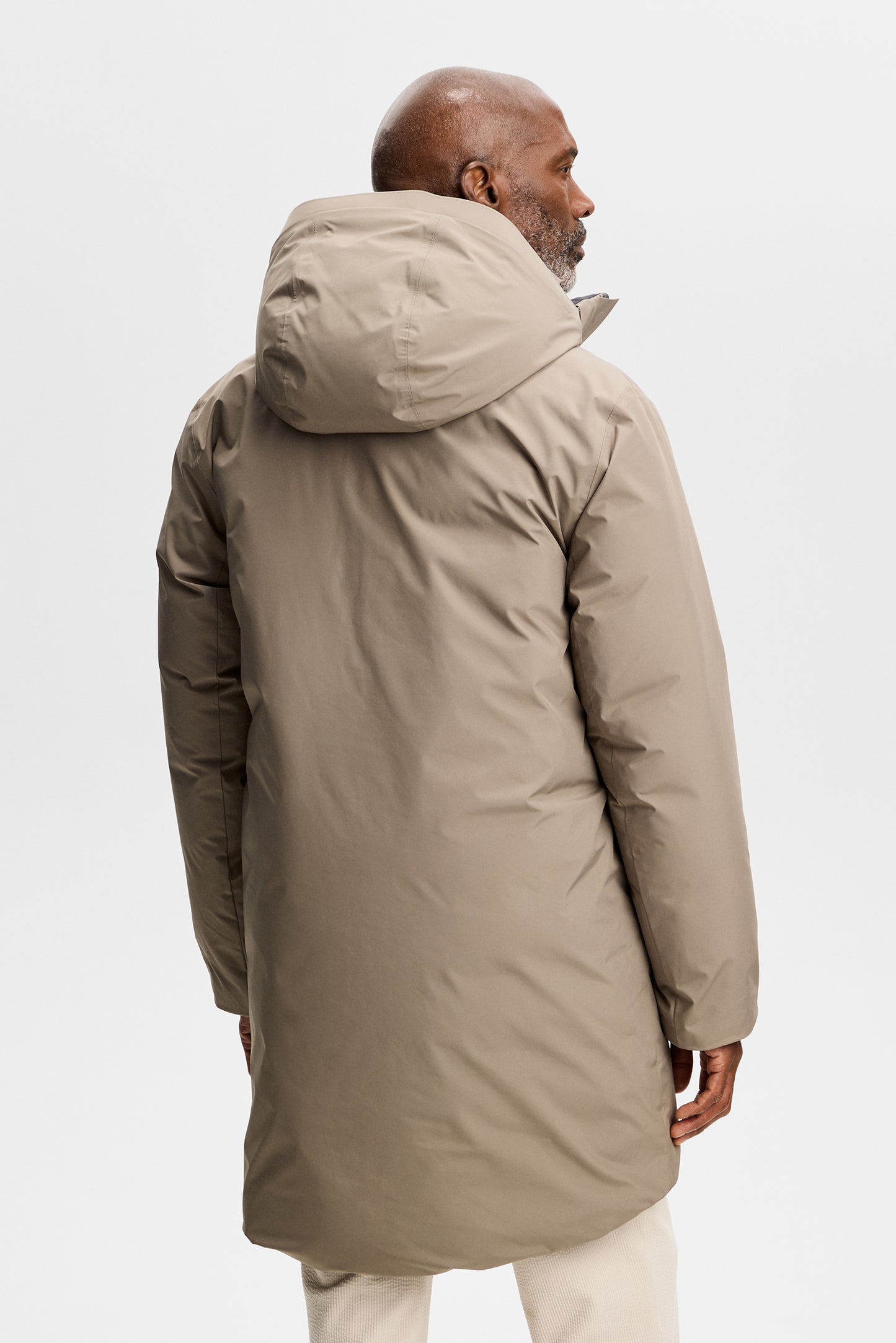 Achteraanzicht: Model draagt de Alon Down Parka in Brindle met capuchon en een lichte broek.