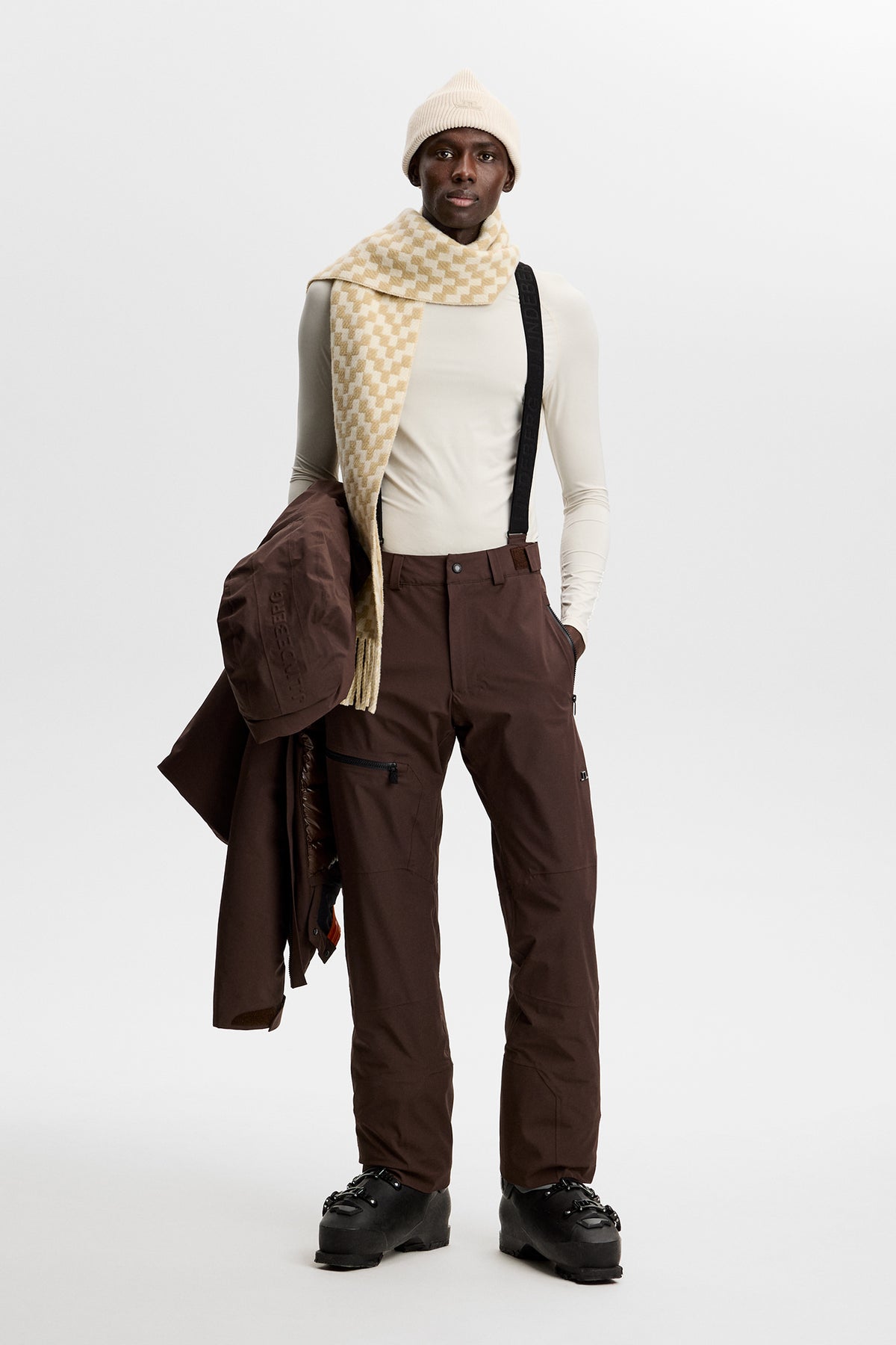 Forfra: Crue Suspender Pant i Seal Brown med sorte seler, lynlåslomme på låret og skistøvler.