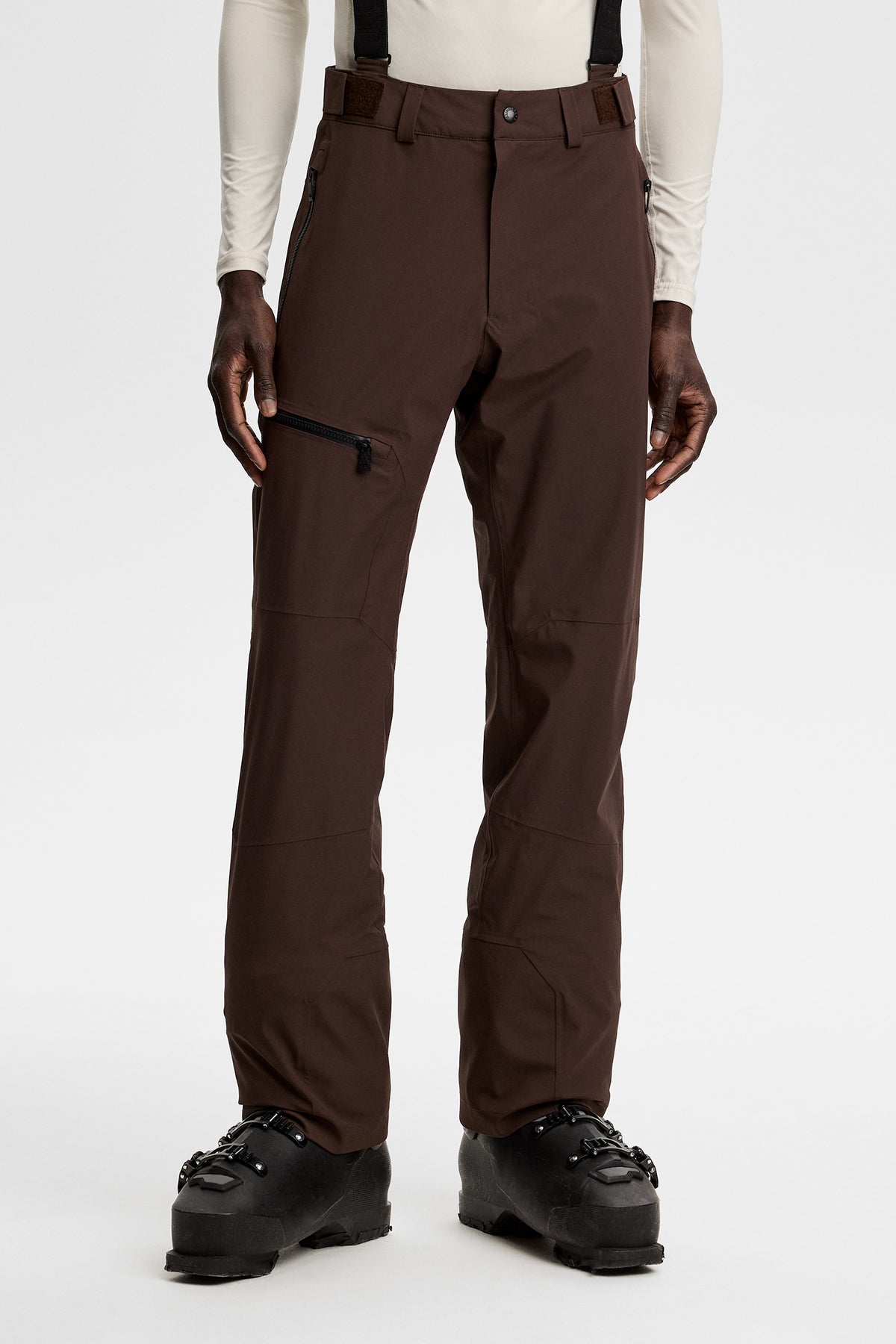 Forfra: Crue Suspender Pant i Seal Brown med justerbare seler, lynlåslommer og skistøvler.
