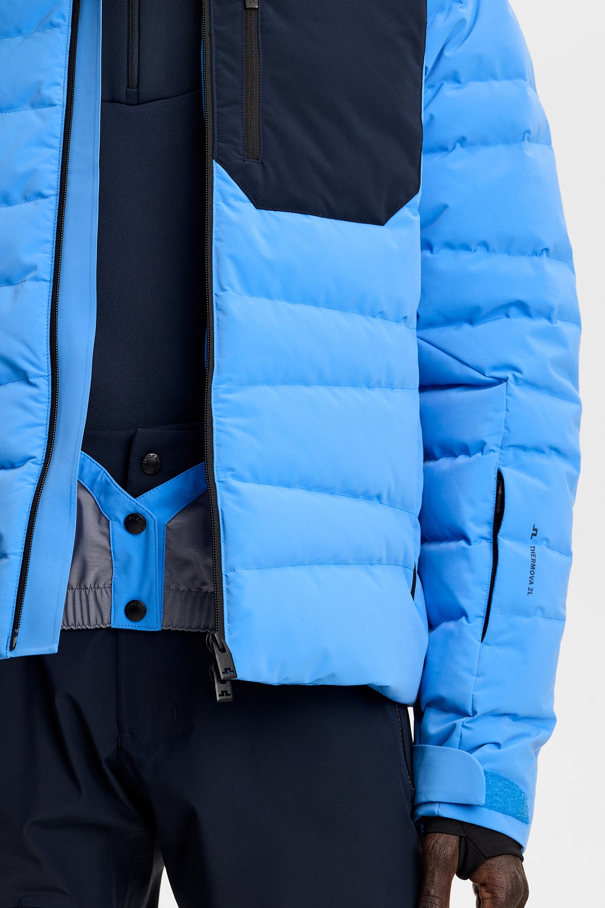 Close-up view: Sonic Blue Thornton Down Jacket showing the quilted design, internal snow gaiter, and sleeve pocket.