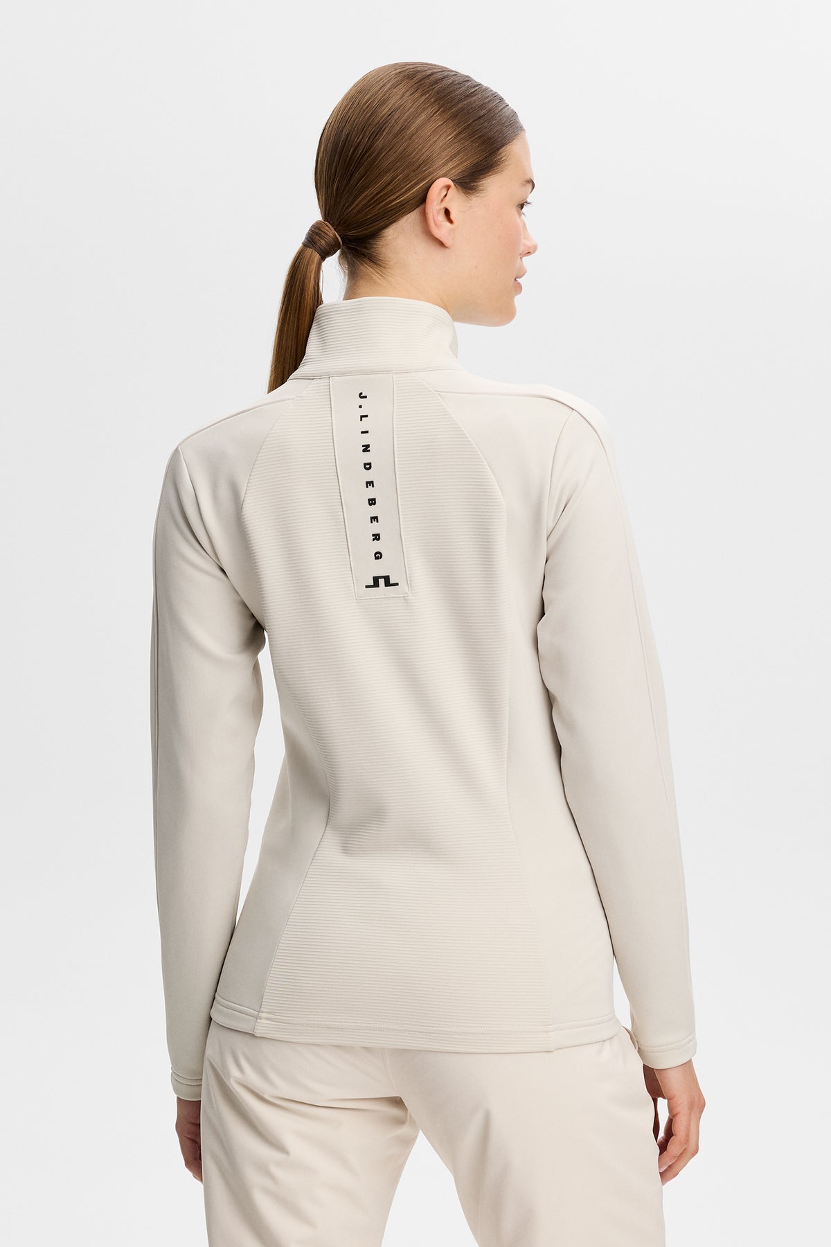 Back view of the Mireya Full Zip Mid Layer in Moonbeam with vertical back logo detail.