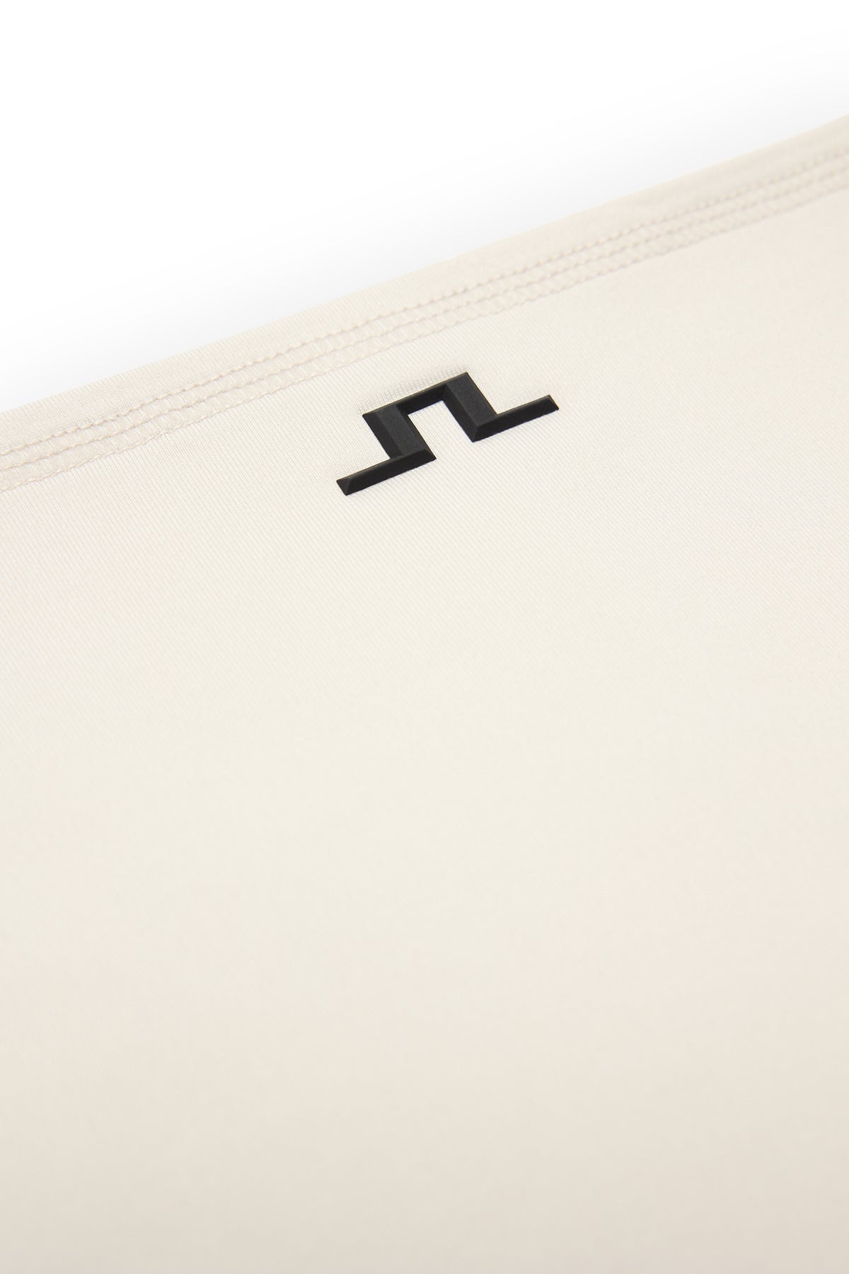Close-up: Rise Neck Gaiter in gebroken wit met zwart Bridge-logo en gestikte zoom.