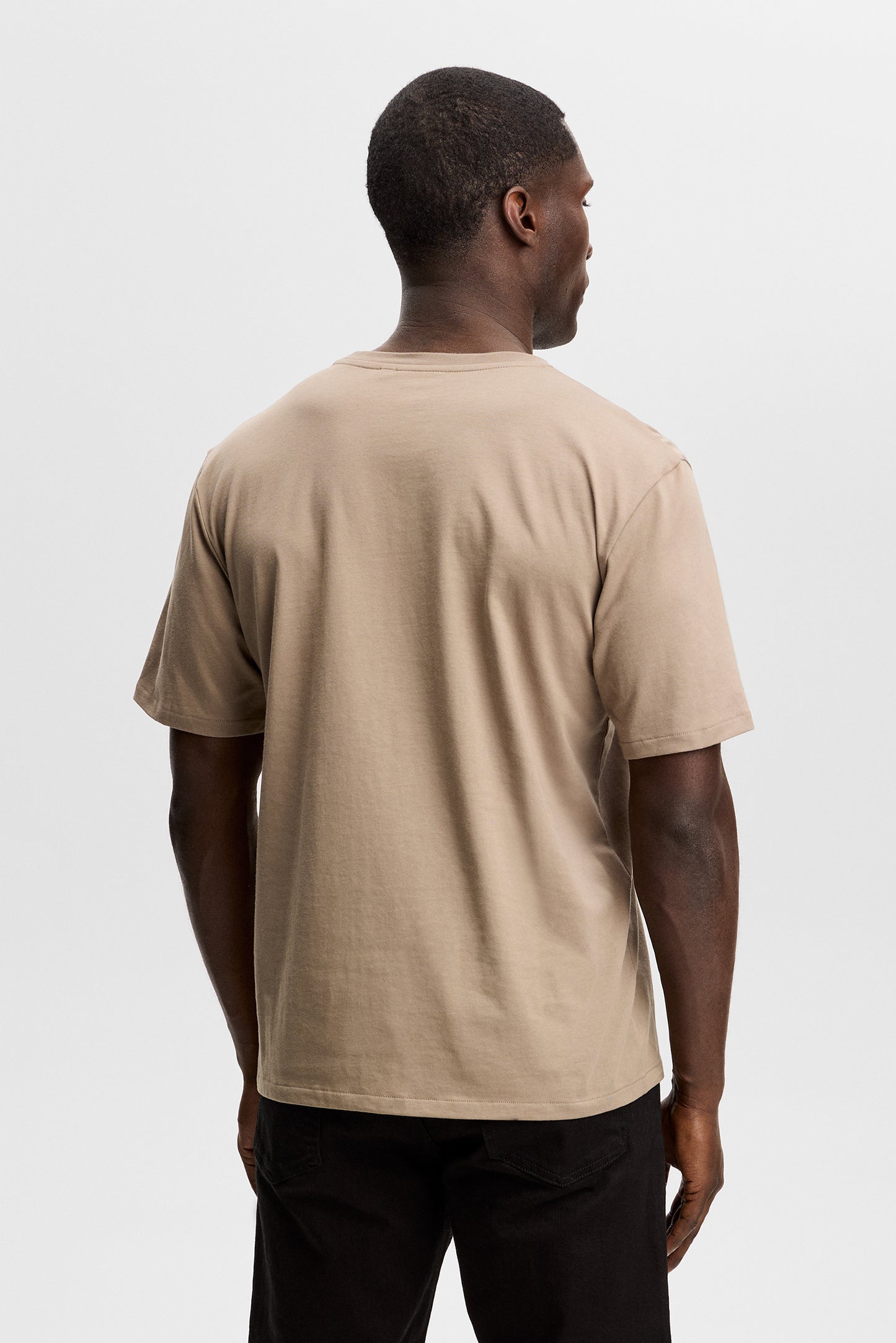 Back view of a model wearing the Alpha Graphic T-shirt in brindle in a studio setting.