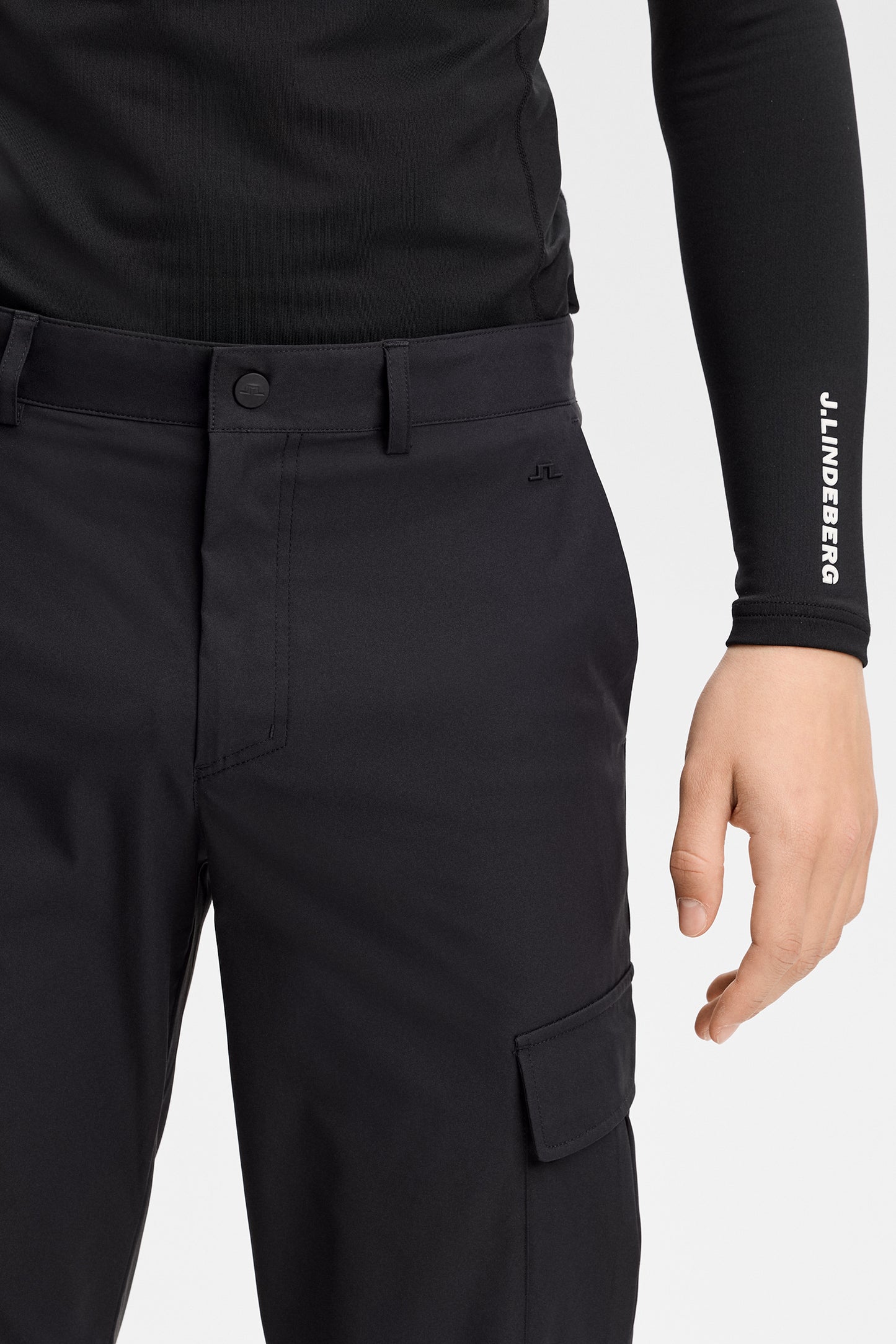 Nærbillede: Sorte Logan Cargo pant foran ved taljen med bæltestropper, lille Bridge-logo og cargolomme.
