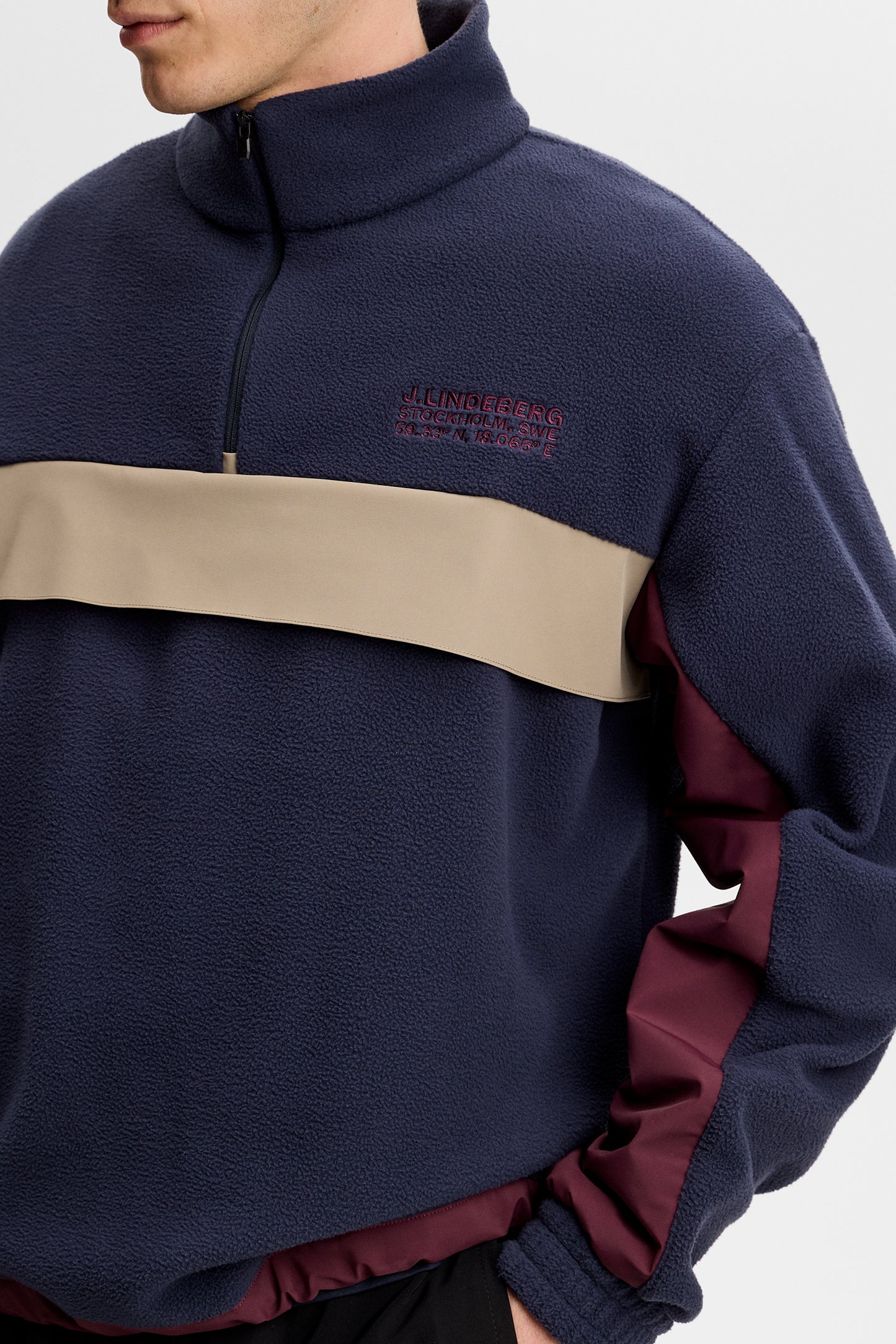 Nærbillede: Quinn Hybrid Sweatshirt i JL Navy med kvartlynlås, beige kontrastpanel og broderet logo på brystet.