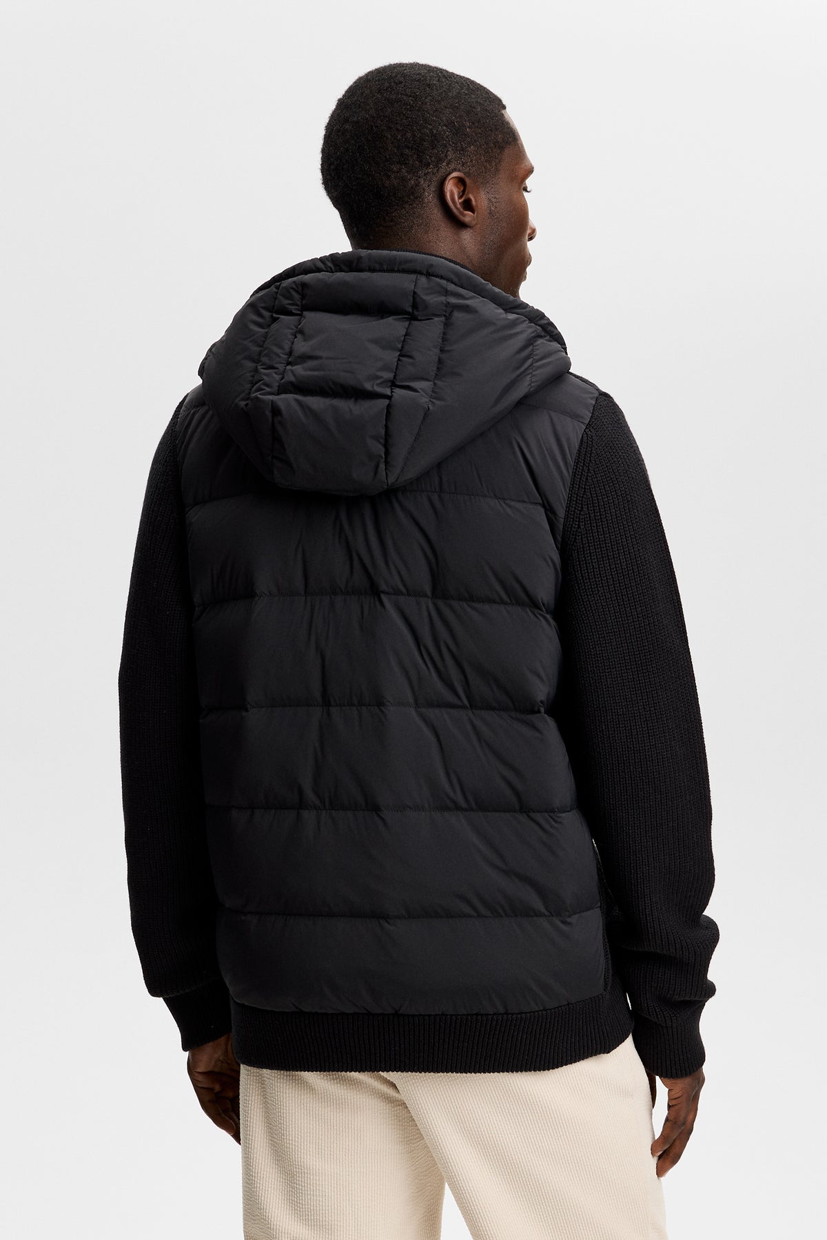 Bakifrån: Dorin Knit Hood Hybrid Jacket i svart med vadderad huva, quiltat ryggparti och stickade ärmar.