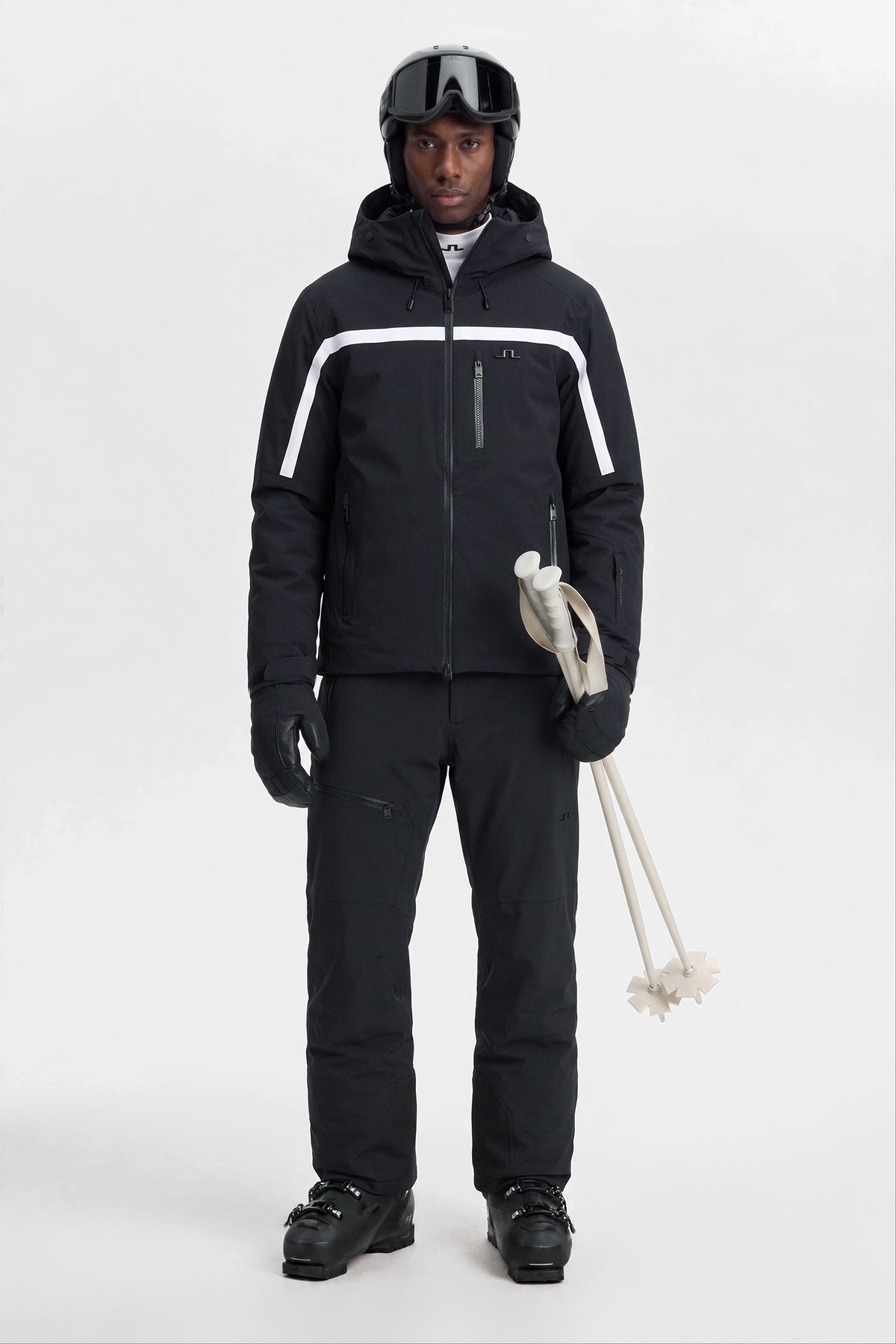 Model wearing the Windsor Jacket in black with a white stripe and Bridge logo in a full-body ski outfit.