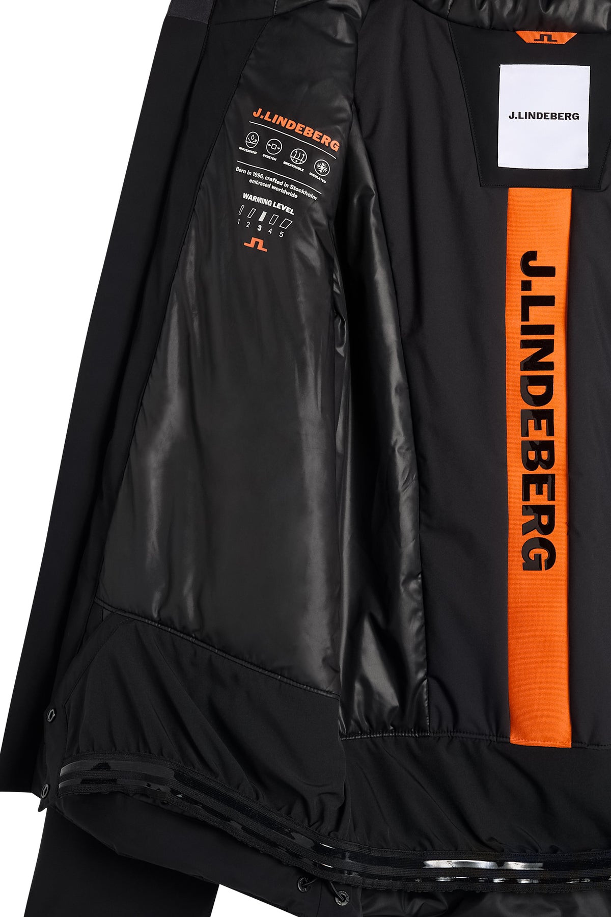 Detail view of the Windsor Jacket in black, showing the interior lining, snow skirt, and orange logo stripe.