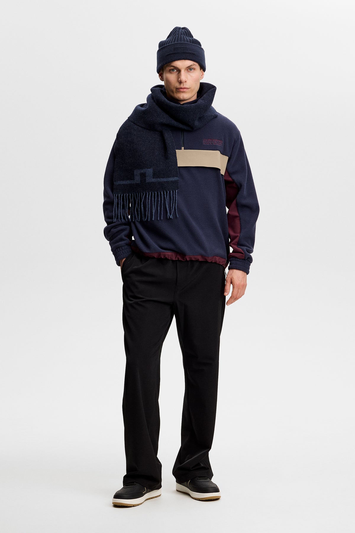 Set forfra: Quinn Hybrid Sweatshirt i JL Navy, båret med hue, halstørklæde og sorte bukser.