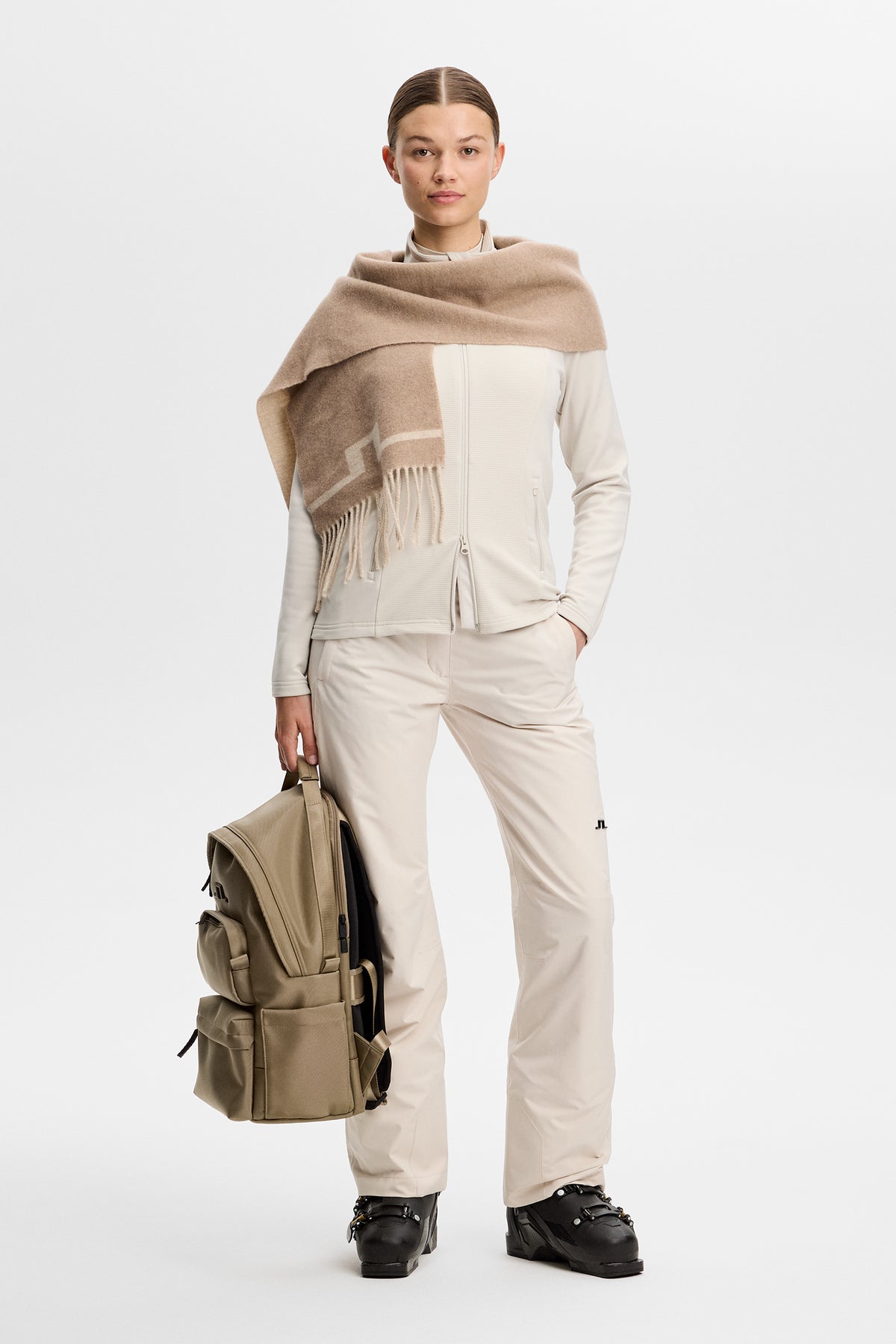 Model wearing the Mireya Full Zip Mid Layer in Moonbeam styled with ski pants in a studio setting.