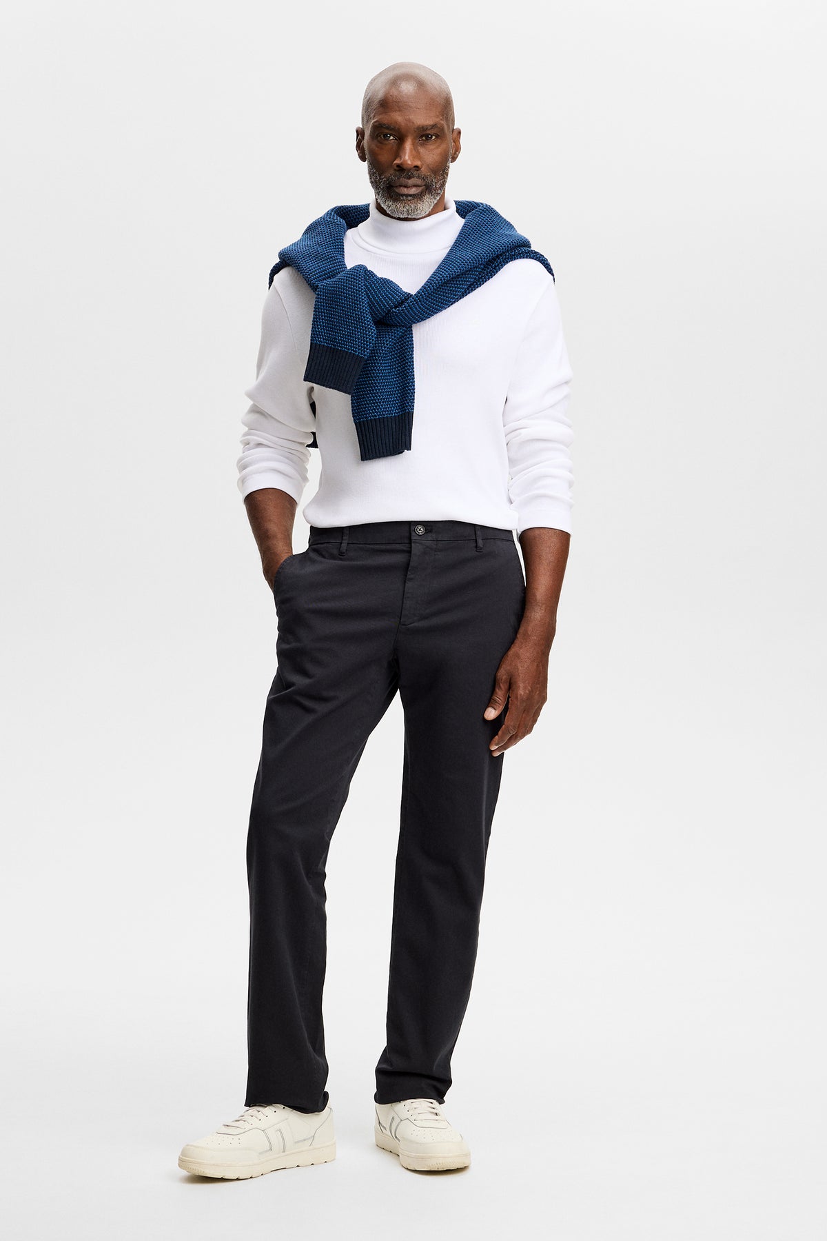 Vue de face : Chaze Cotton Stretch Pants GD noir en coupe regular, porté avec un haut blanc et des baskets.