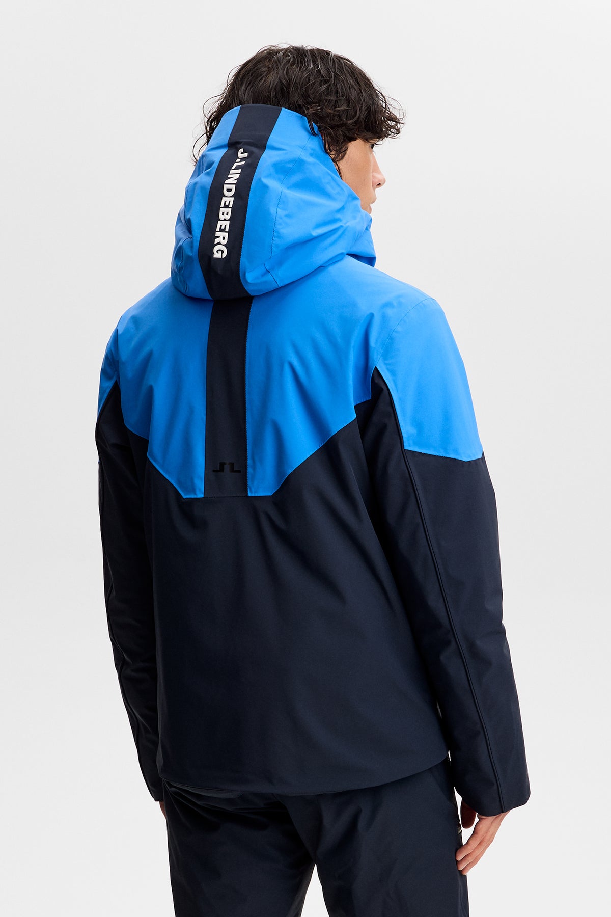 Rückansicht: Caldwell Jacket in Sonic Blue im Colorblock-Design mit J.LINDEBERG-Schriftzug an der Kapuze.