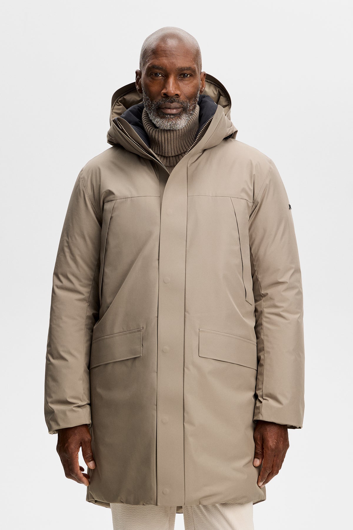 Vooraanzicht: Model draagt de Alon Down Parka in Brindle met capuchon over een geribde coltrui.