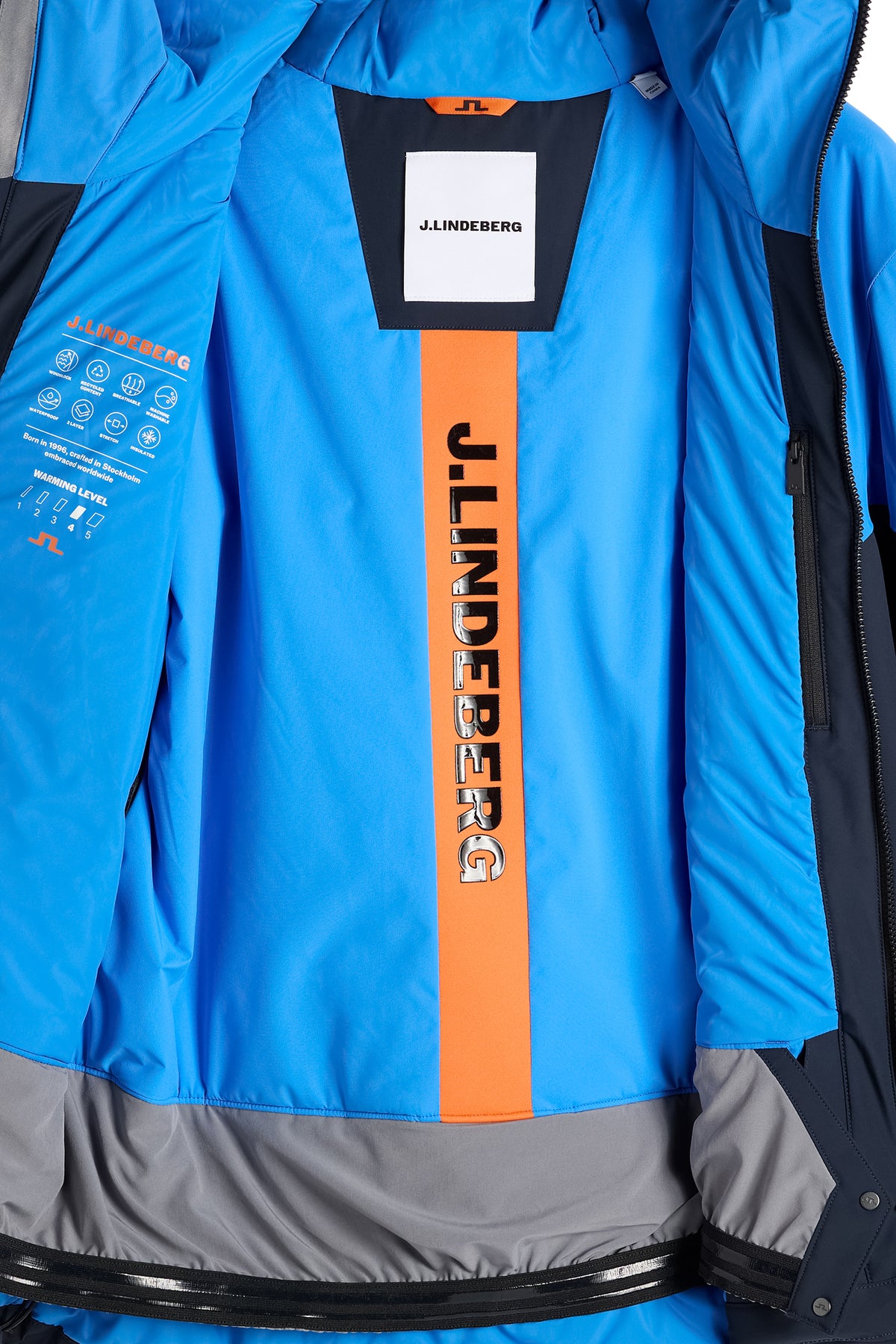 Innenansicht: Caldwell Jacket in Sonic Blue mit blauem Futter, orangem J.LINDEBERG-Schriftzug und Schneefang.
