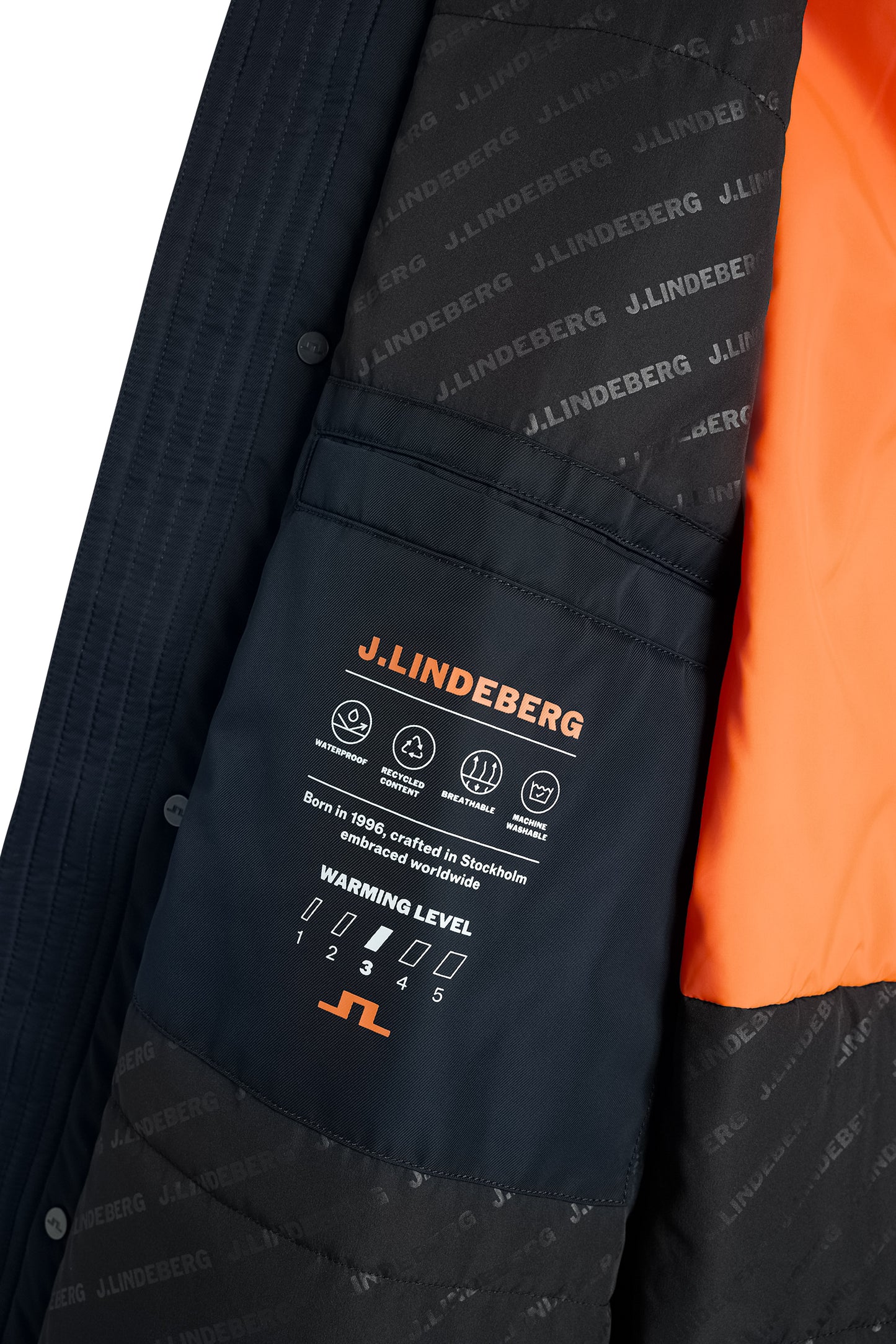 Close-up of the Harold Padded Jacket in JL Navy, showing the interior pocket with orange printed details and logo lining.