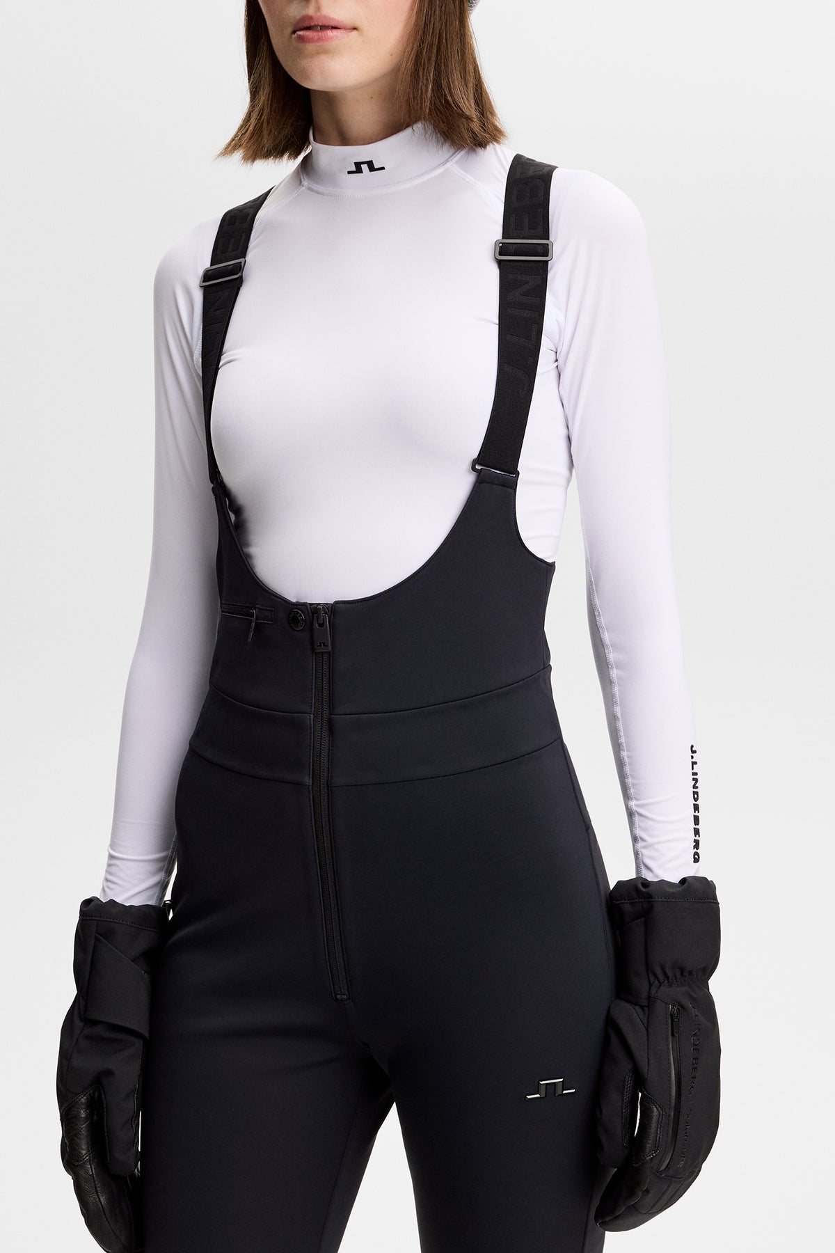 Close-up: Zwarte Aviana Softshell Bib Pant met logobretels, ritssluiting aan de voorkant en Bridge-logo.