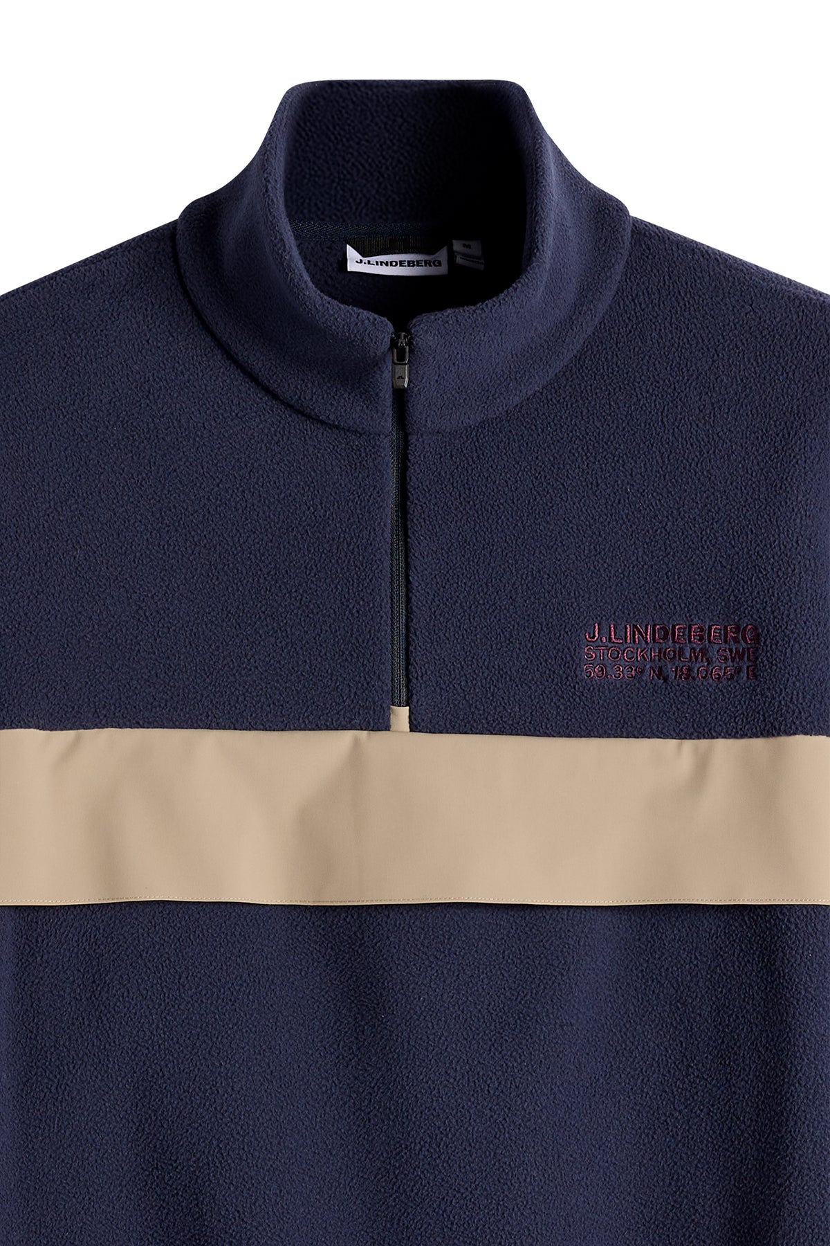 Nærbillede: Quinn Hybrid Sweatshirt i JL Navy med kvartlynlås, beige kontrastpanel og broderet logo på brystet.