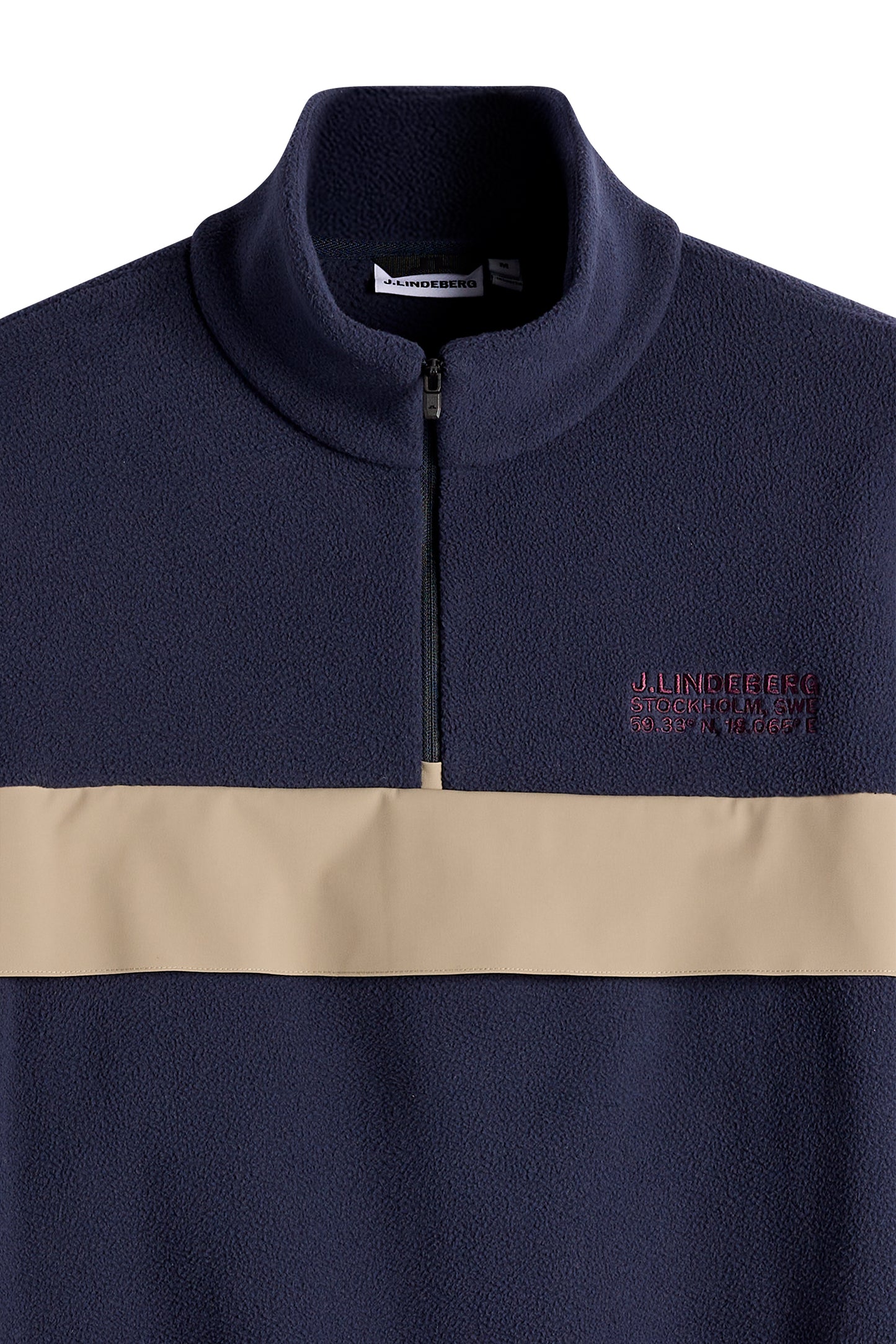 Nærbillede: Quinn Hybrid Sweatshirt i JL Navy med kvartlynlås, beige kontrastpanel og broderet logo på brystet.
