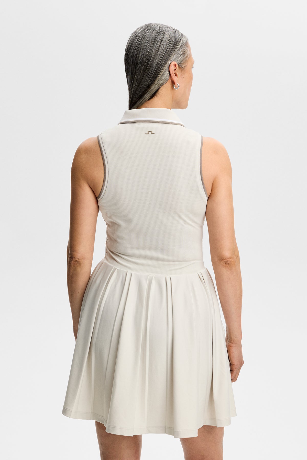 Achteraanzicht: Model draagt de mouwloze Swing Dress in Moonbeam met geplooide rok en Bridge-logo in de nek.