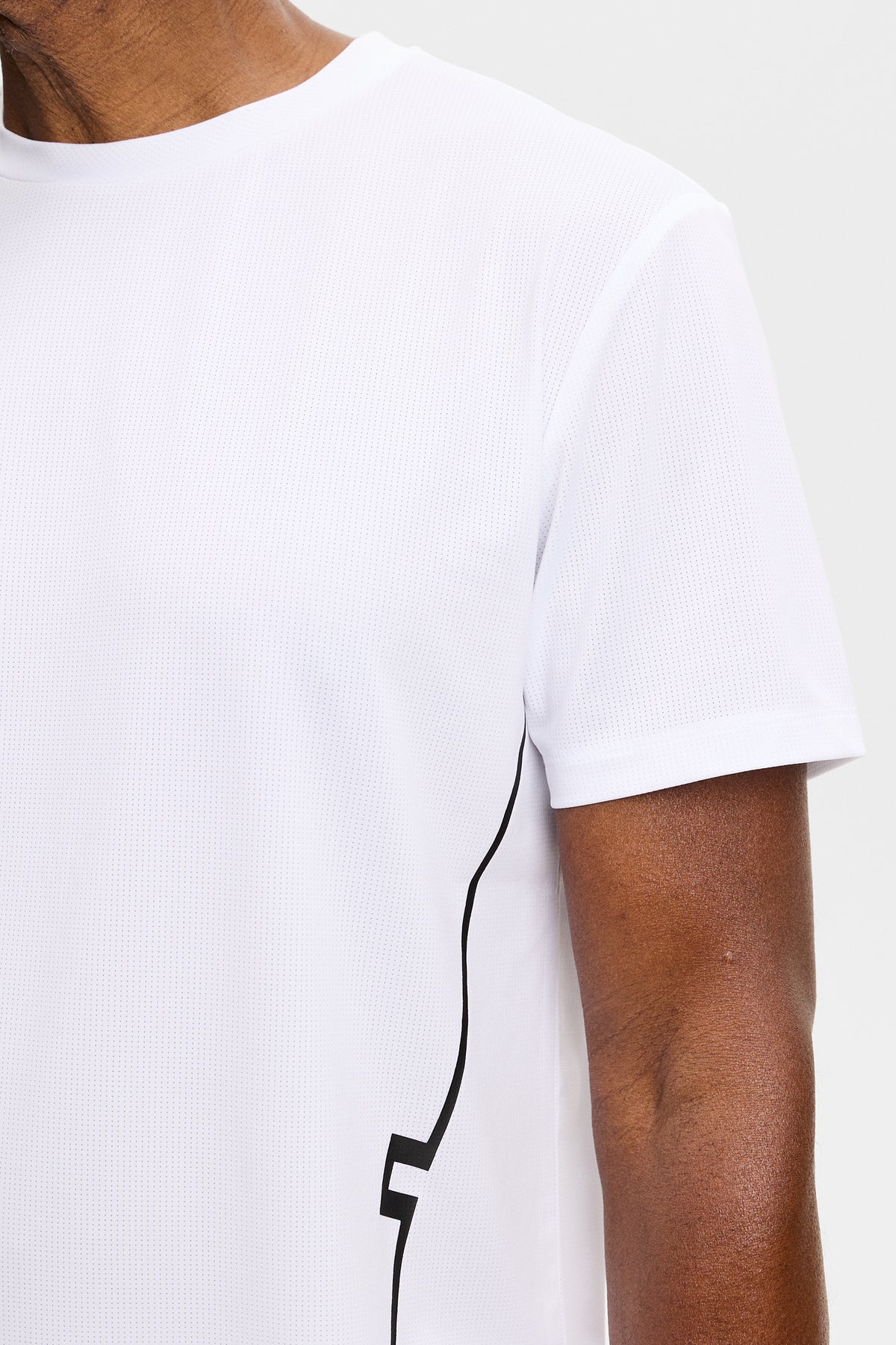 Close-up: Wit Leroy T-shirt met ronde hals, mesh-structuur en zwart lijndetail aan de zijkant.