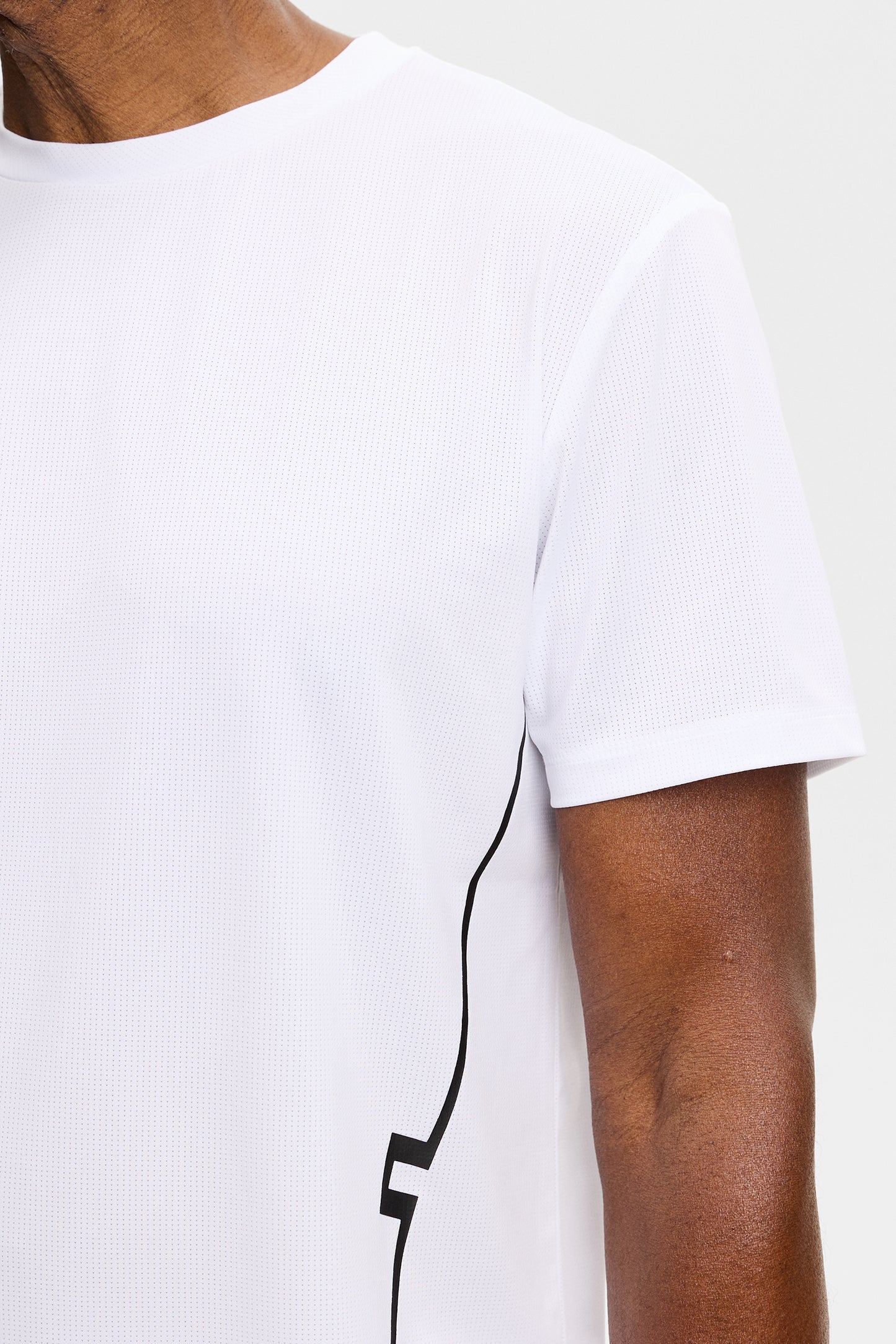 Close-up: Wit Leroy T-shirt met ronde hals, mesh-structuur en zwart lijndetail aan de zijkant.