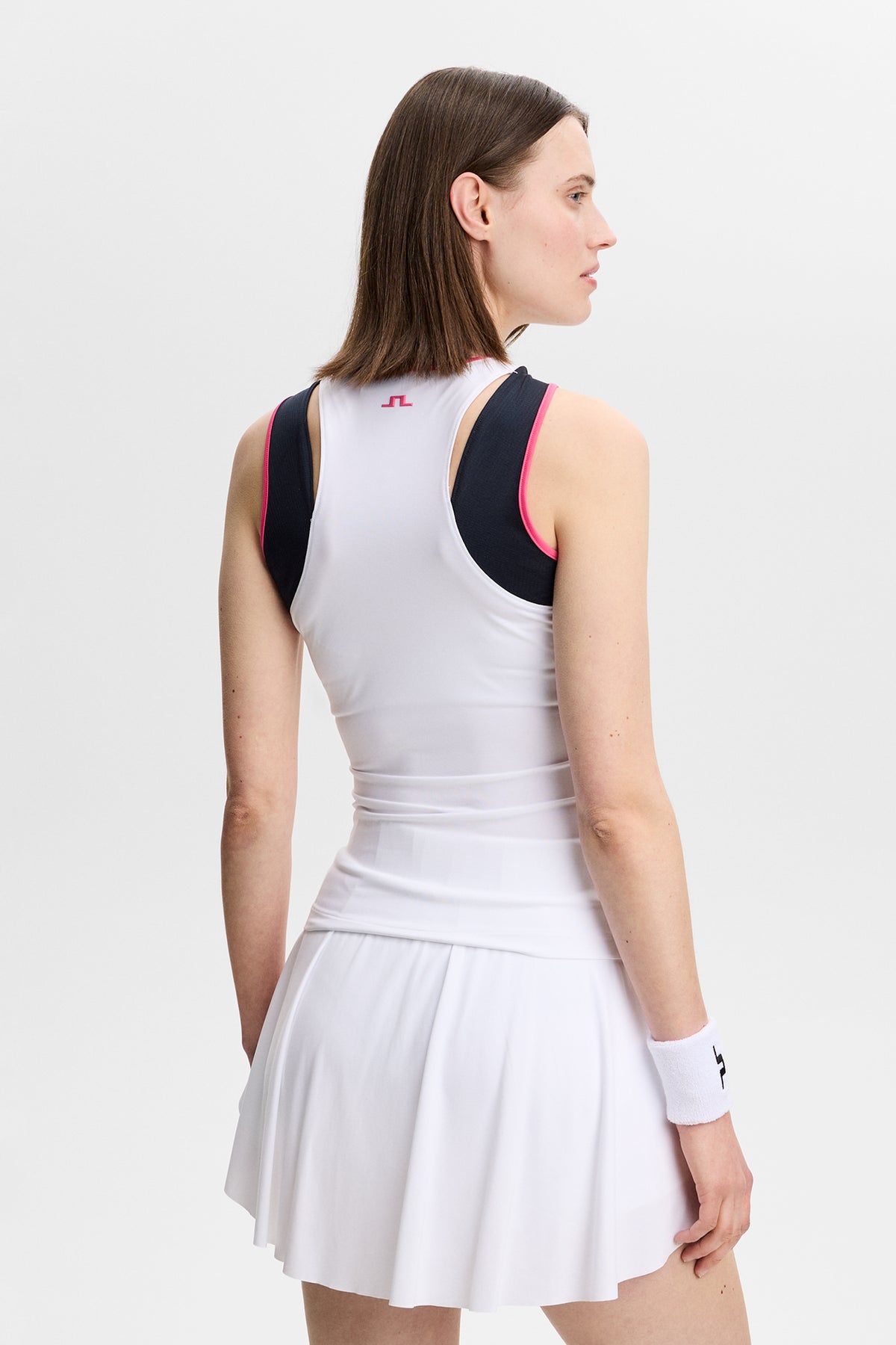 Rückansicht: Weißes Ava Sleeveless Top mit pinker Kontrasteinfassung und Bridge-Logo am Nacken.