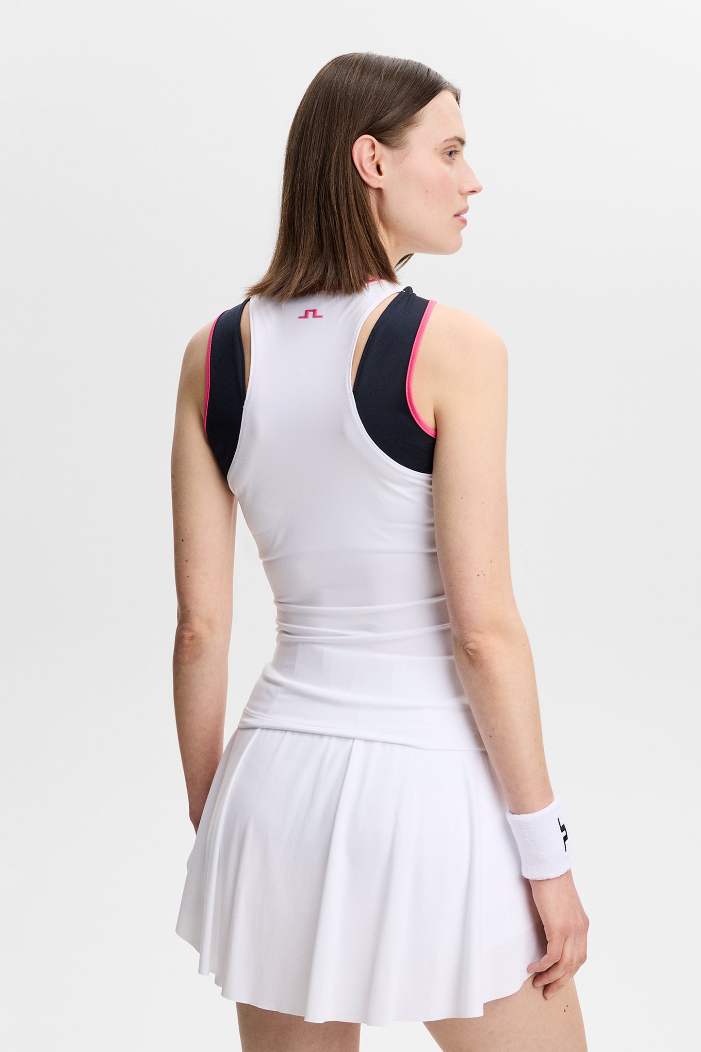 Rückansicht: Weißes Ava Sleeveless Top mit pinker Kontrasteinfassung und Bridge-Logo am Nacken.