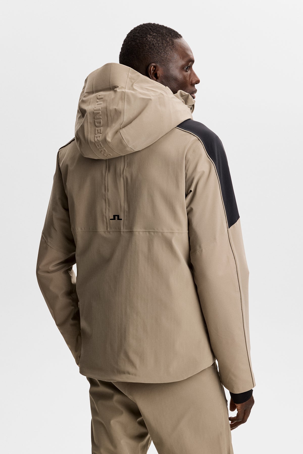 Set bagfra: Greyson Down Jacket i Brindle med hætte, J.LINDEBERG-logo og sort Bridge-logo på ryggen.