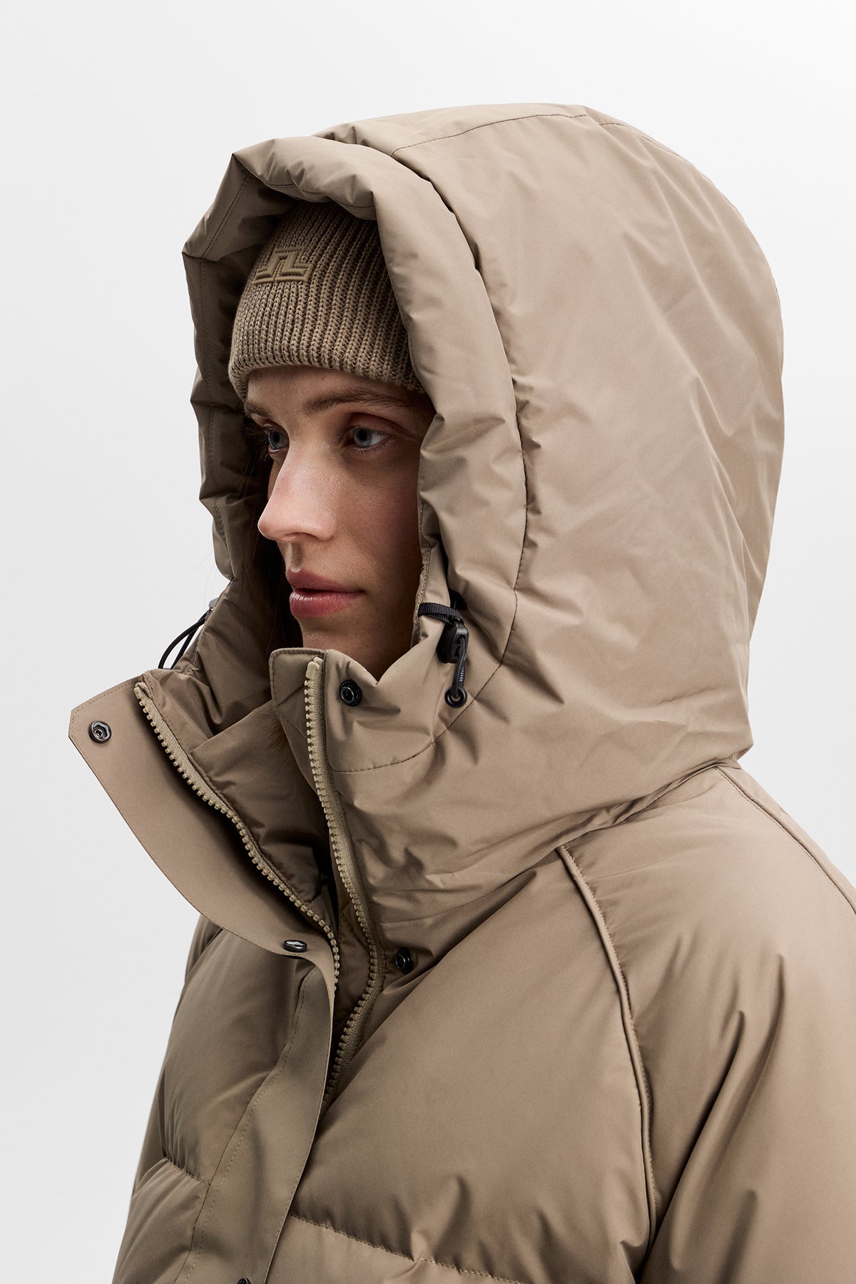 Gros plan : Lea Down Jacket en Brindle avec capuche réglable relevée et col montant zippé.