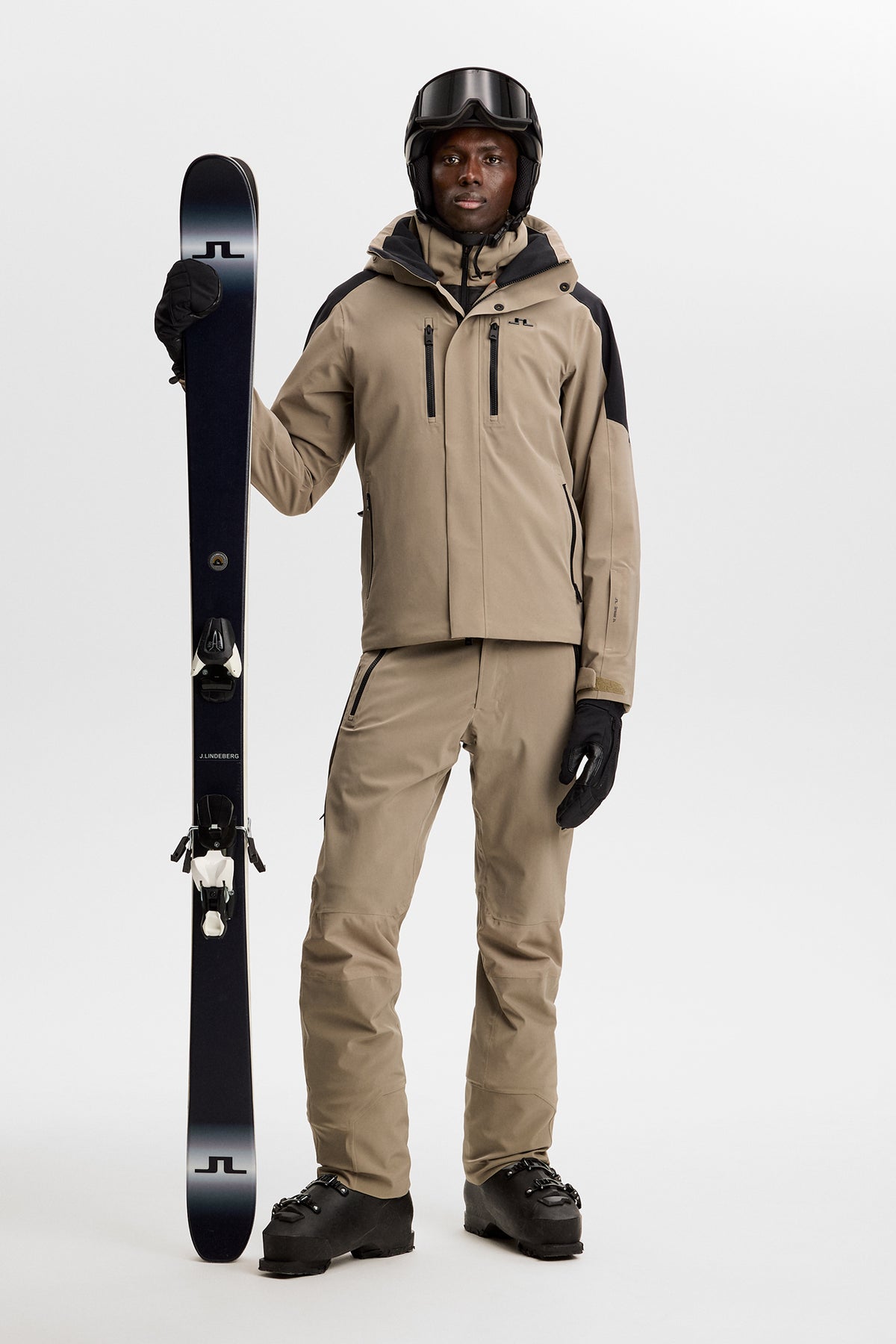 Helbillede: Greyson Down Jacket i beige med sorte detaljer, båret med matchende skibukser og ski.