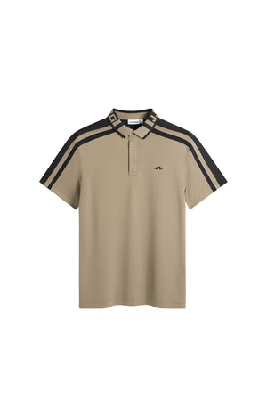 Framifrån: Bo Polo i beige med jacquardkrage, knappslå med tre knappar, randiga axelpaneler och Bridge-logotyp.
