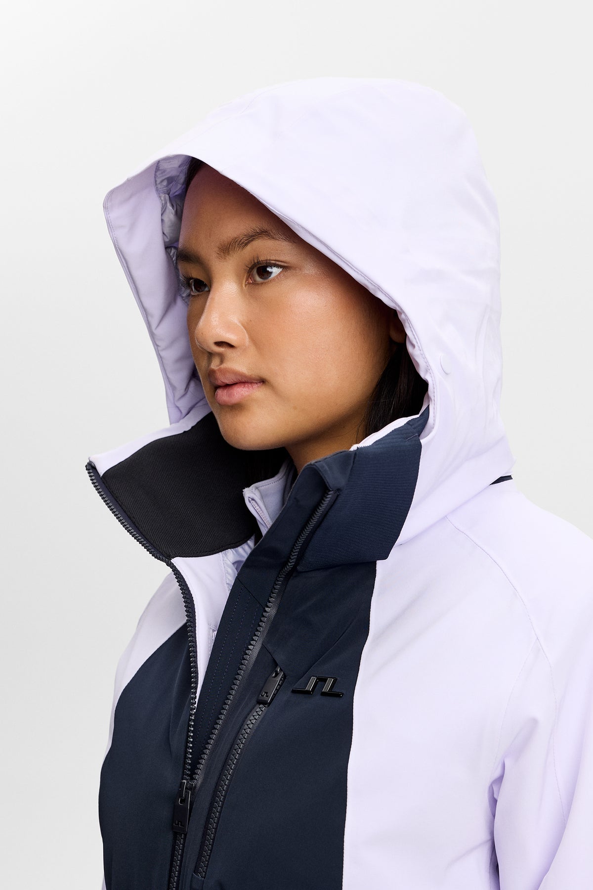 Nahaufnahme: Soleil Down Jacket in Purple Heather mit aufgesetzter Kapuze, hohem Kragen und Bridge-Logo auf der Brust.
