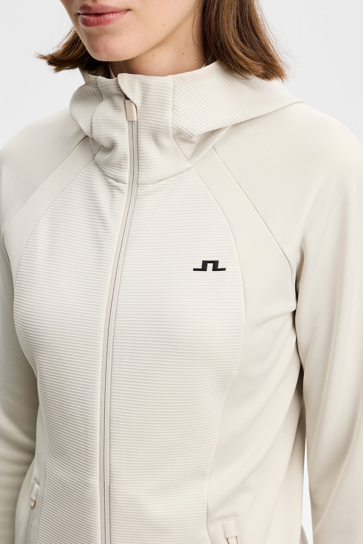 Close-up of the Mireya Full Zip Hood in Moonbeam, highlighting the textured chest panel and Bridge logo.