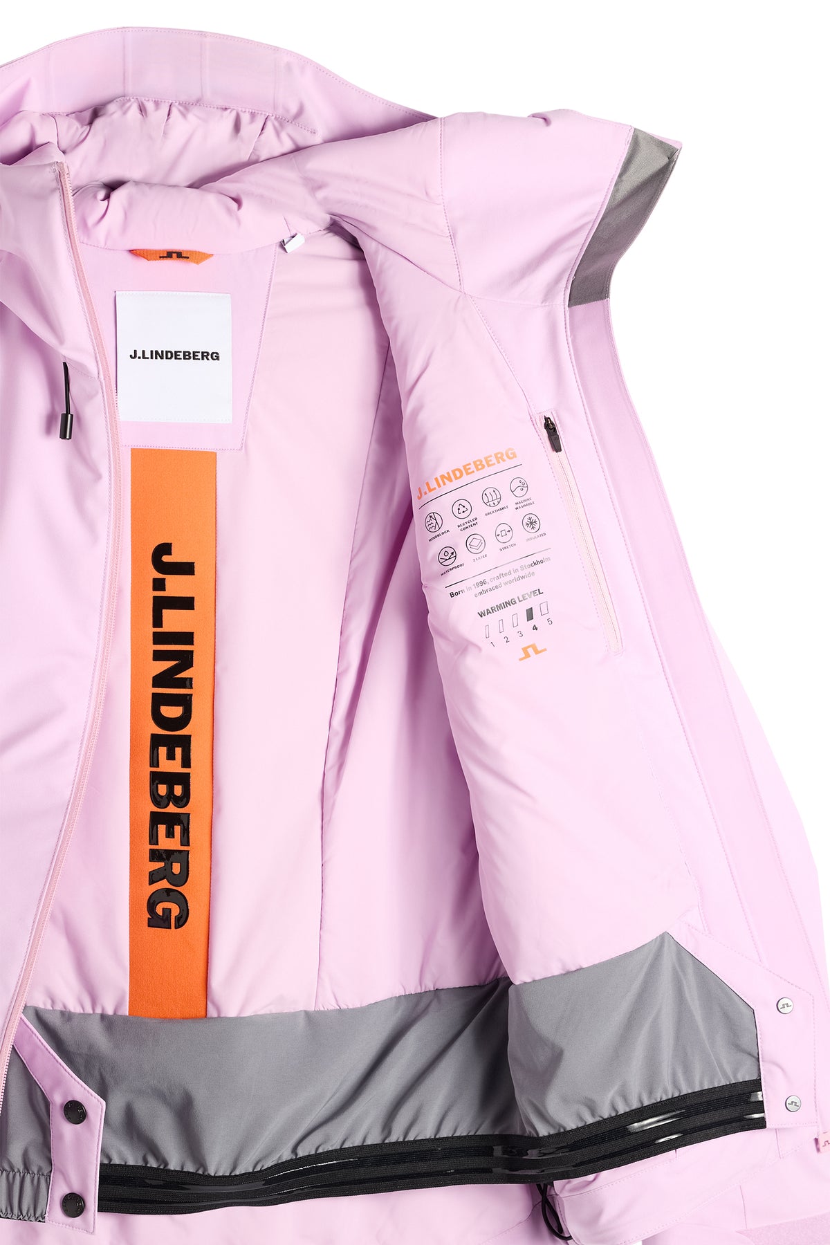 Nærbillede: Indersiden af Lilia Jacket i Orchid Bouquet med orange J.LINDEBERG-logobånd, inderlomme og snefang.