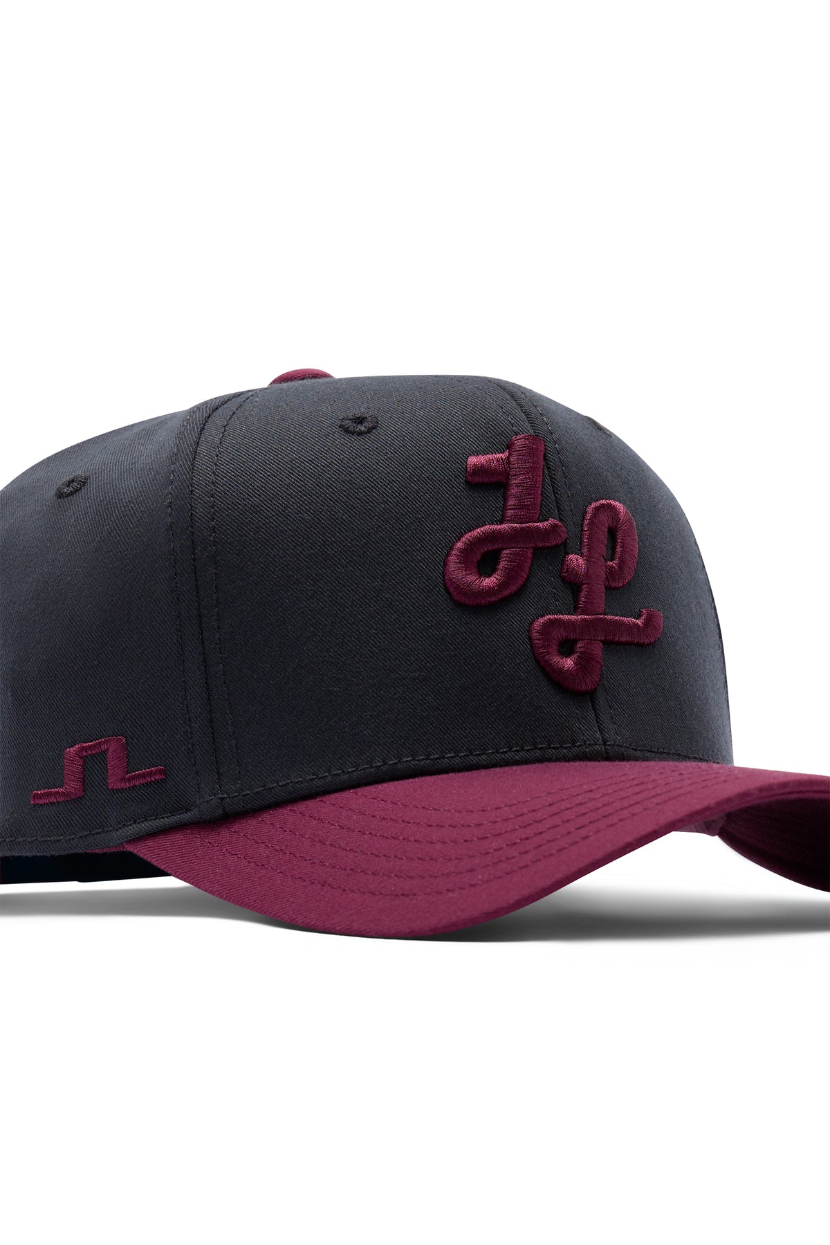 Close-up: Boyd Cap in JL Navy met bordeauxrode klep, 3D-geborduurd logo en Bridge-logo op de zijkant.
