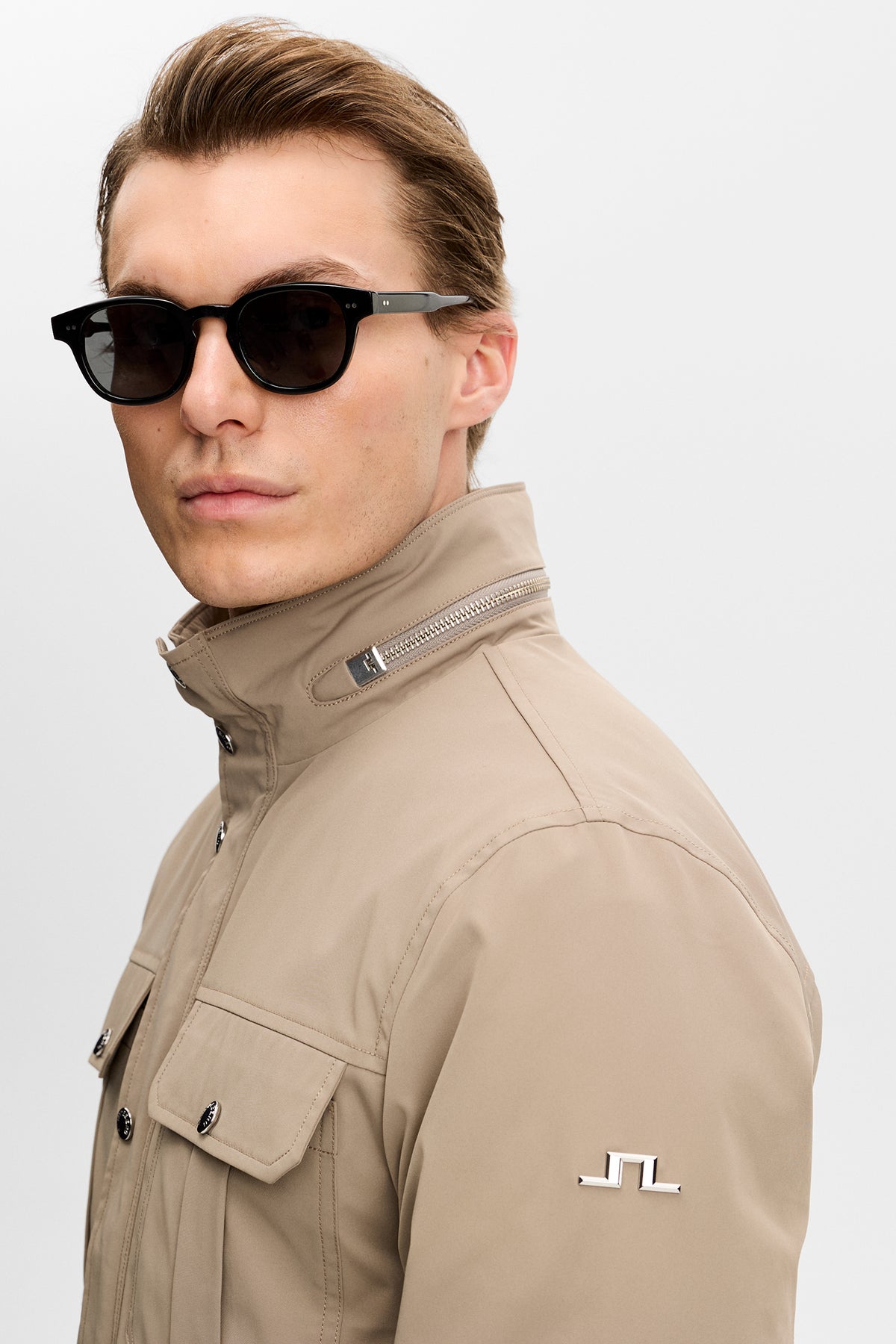 Close-up view: Bailey Recy Poly Jacket in Brindle showing collar zip, chest pocket, and Bridge logo on the sleeve.