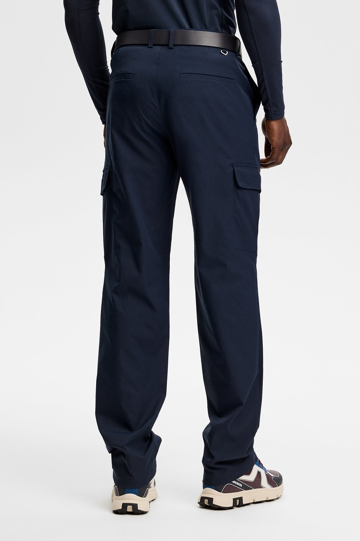 Model wearing the Logan Cargo pant in JL Navy, back view showing side cargo pockets in a studio setting.