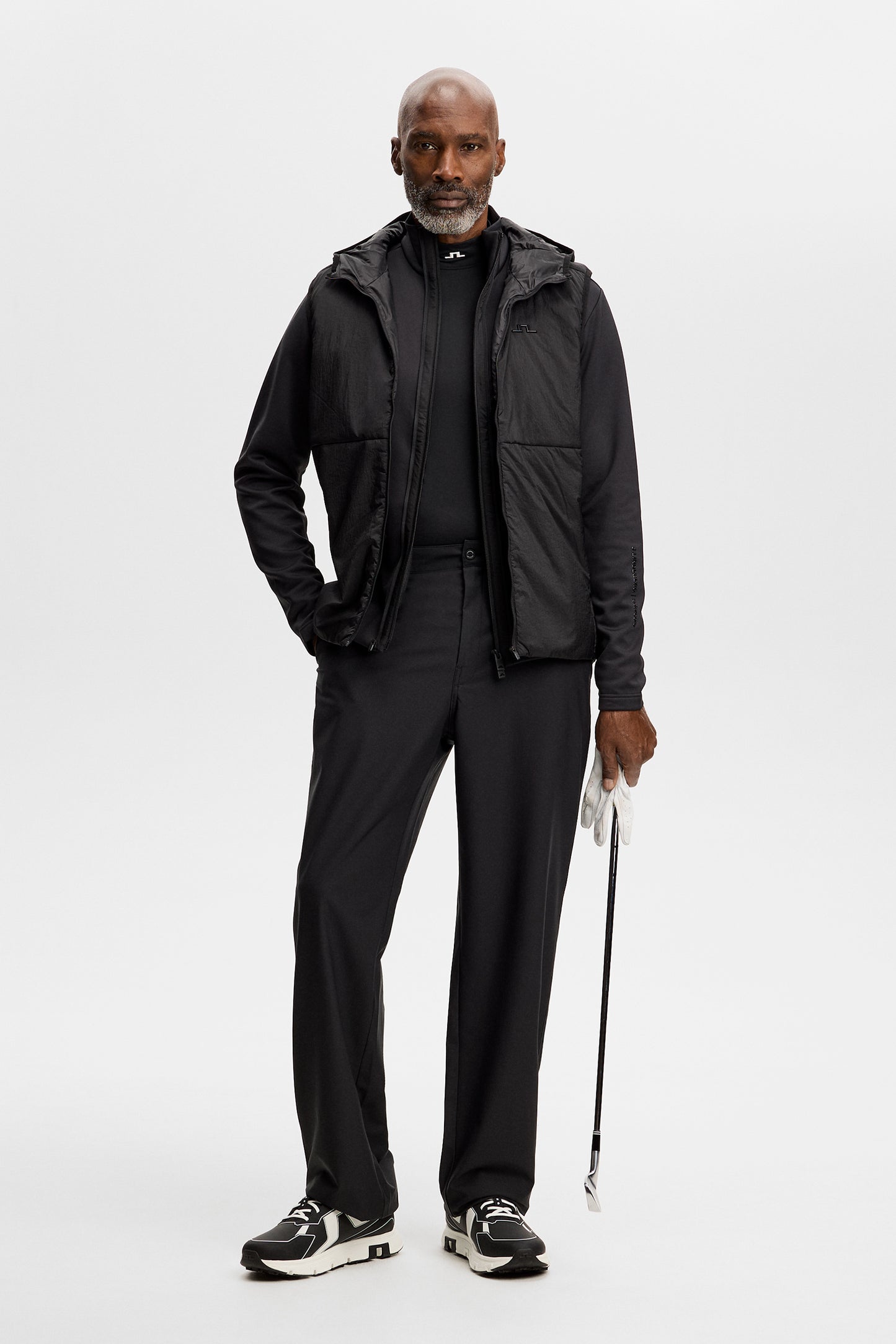 Vorderansicht: M Solarcore 3 in 1 Jacket in Schwarz an einem Model, kombiniert mit schwarzer Hose und Golfschläger.