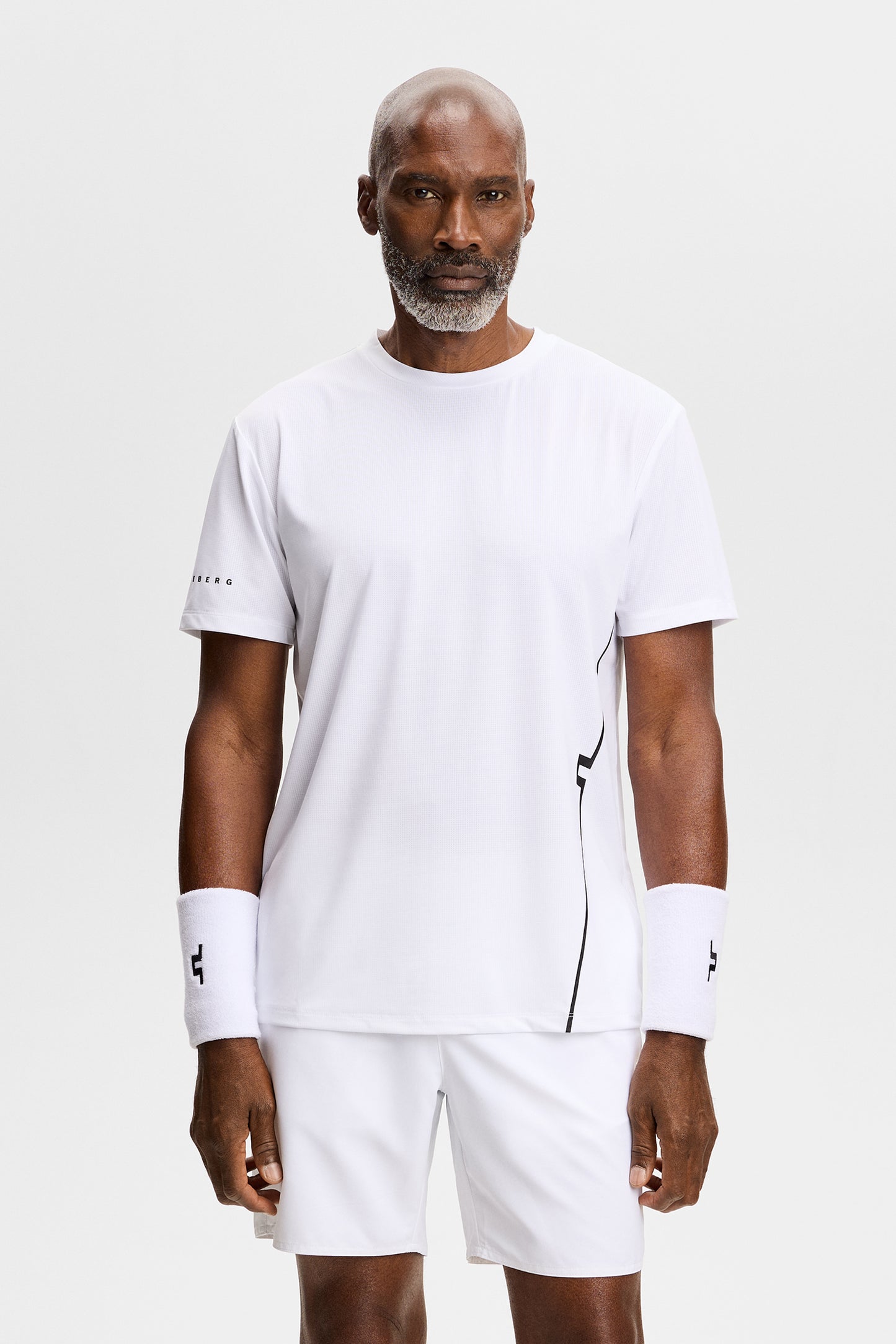 Vooraanzicht: Model draagt het witte Leroy T-shirt met korte mouwen, ronde hals en zwarte lijn aan de zijkant.