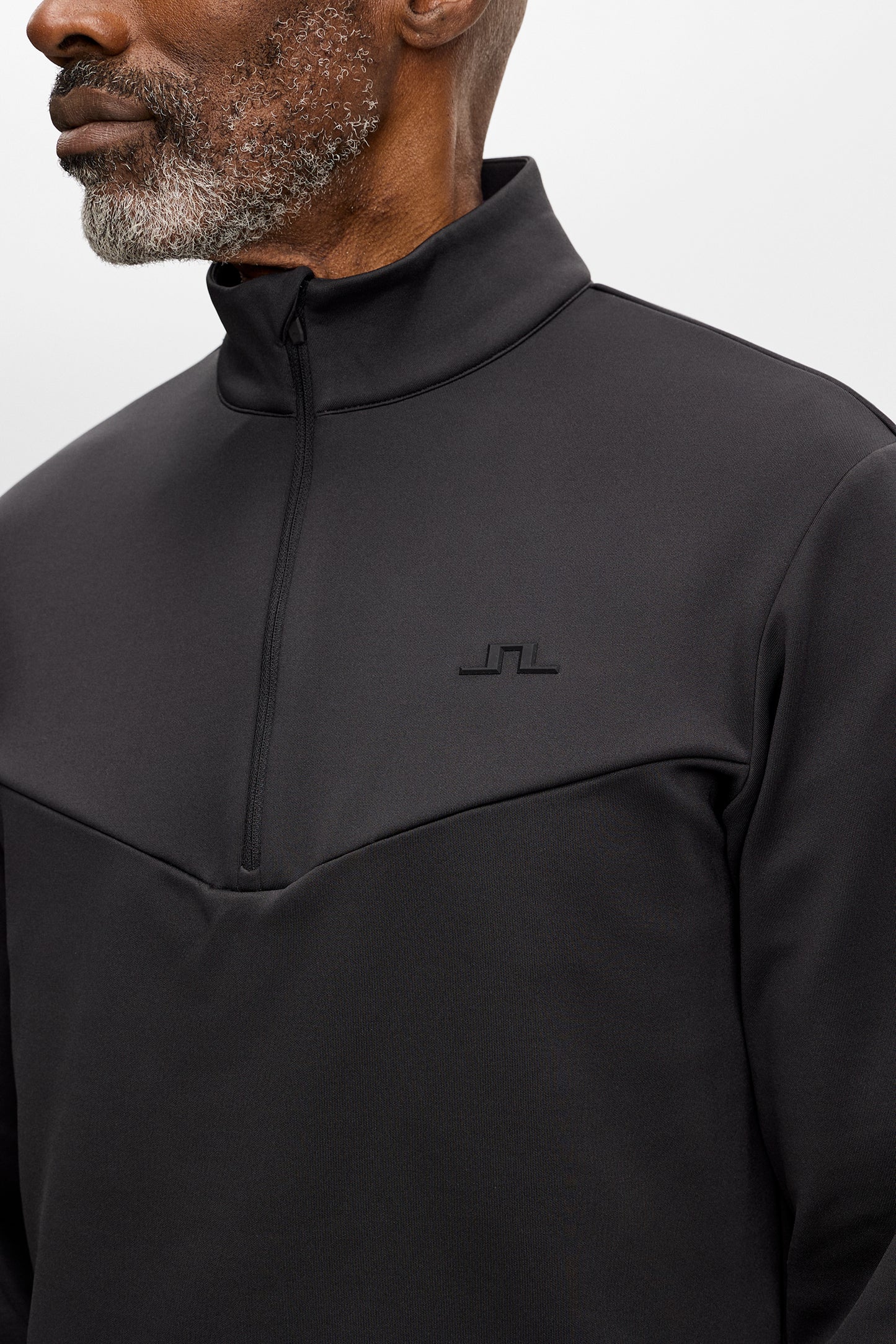 Närbild: Maclean Quarter Zip Mid Layer i Black med halv dragkedja, ståkrage och Bridge-logotyp på bröstet.