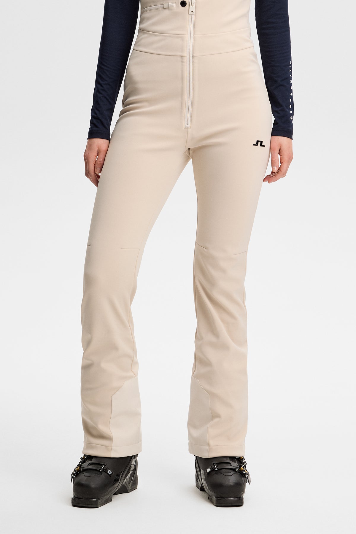 Vooraanzicht: Model draagt de Aviana Softshell Bib Pant in Moonbeam met Bridge-logo op het linkerbeen.