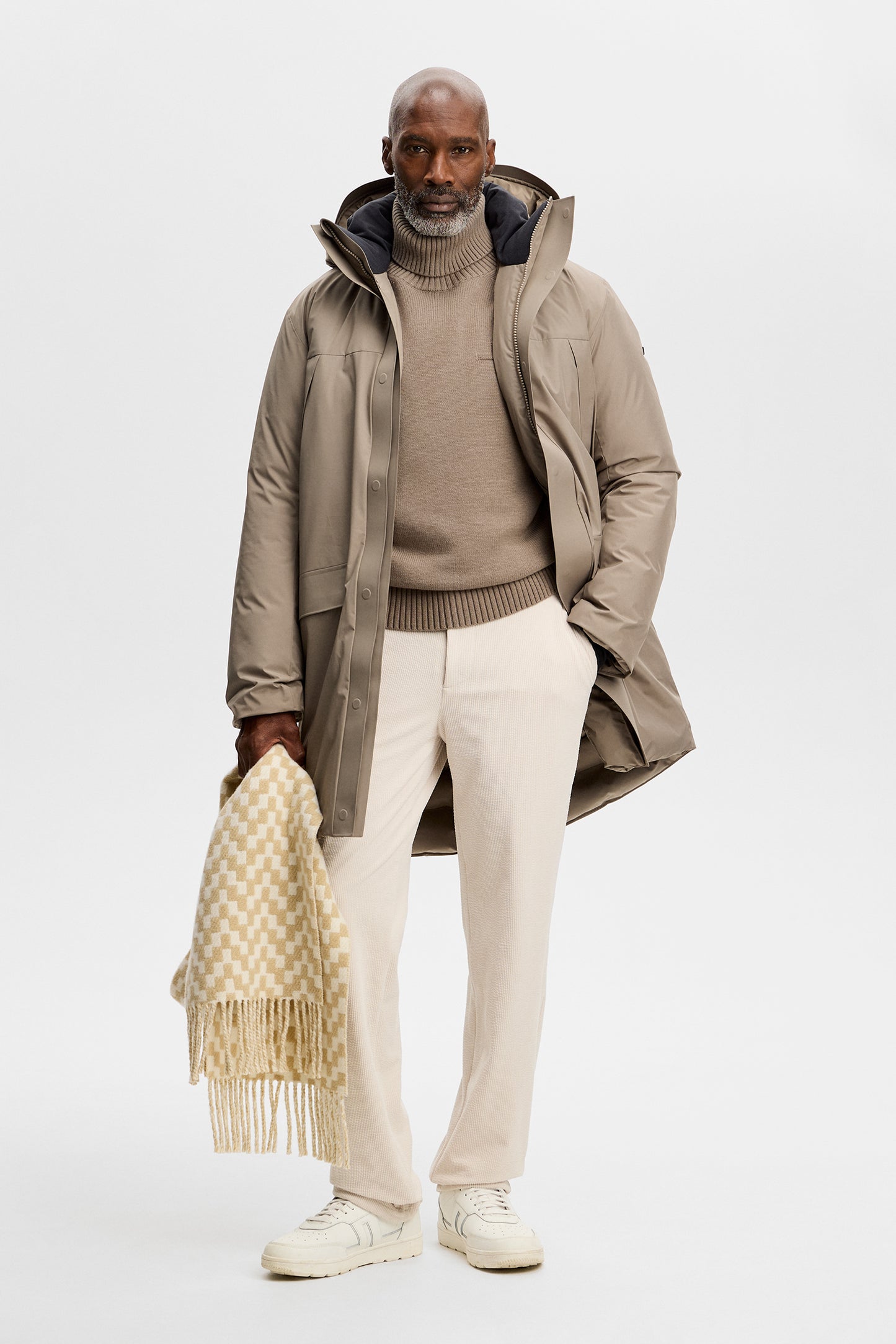 Vooraanzicht: Model draagt de Alon Down Parka in Brindle open over een beige coltrui en lichte broek.