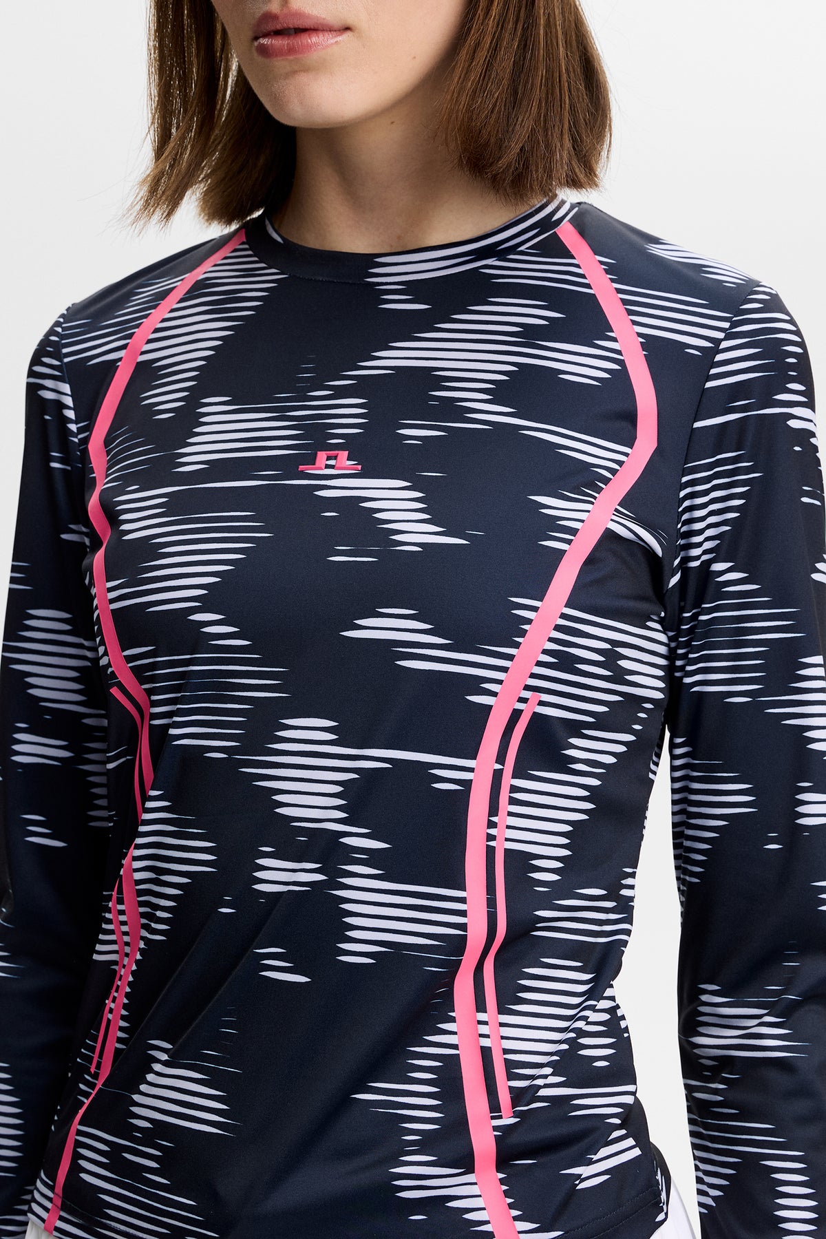 Close-up: Line LS Printed Top met grafische print, roze contrasterende lijnen en Bridge-logo op de borst.