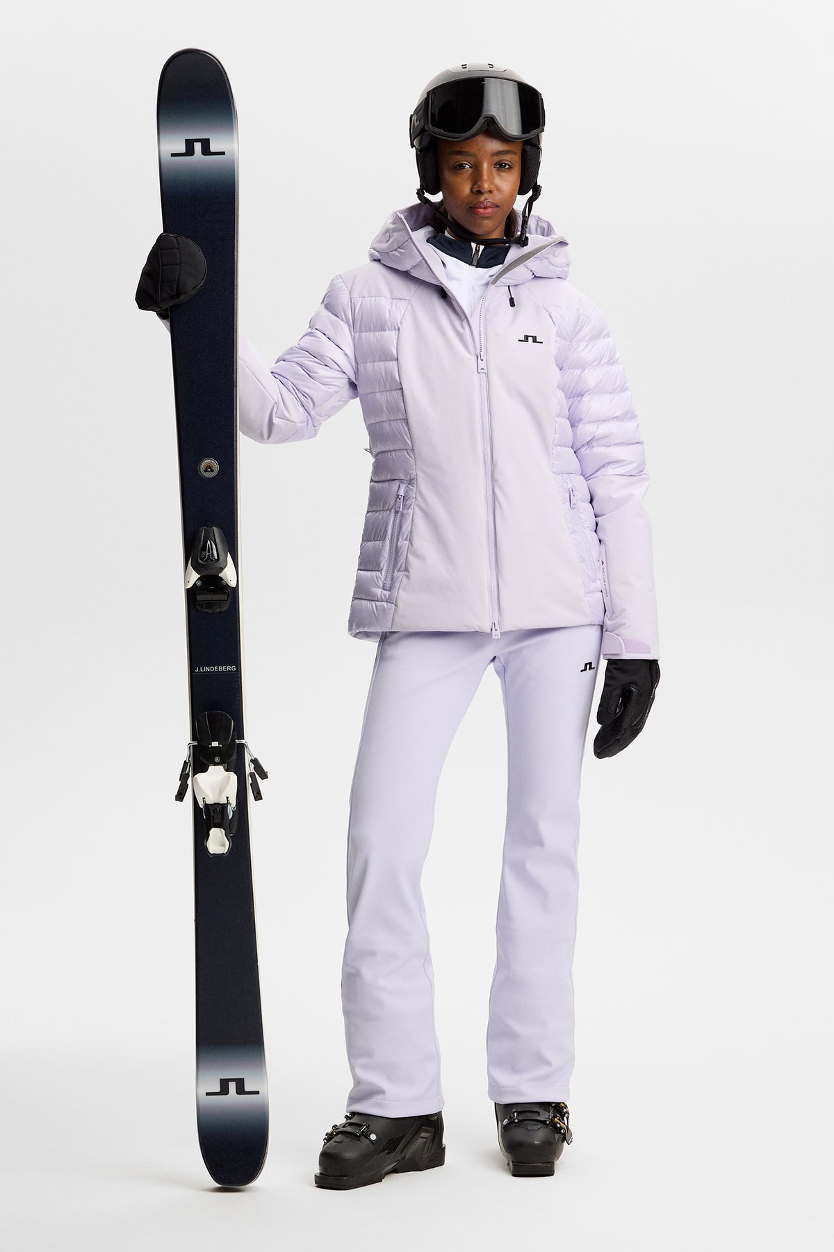 Helsfigur: Maelle Down Jacket i Purple Heather med hætte og Bridge-logo, stylet med skibukser og ski.